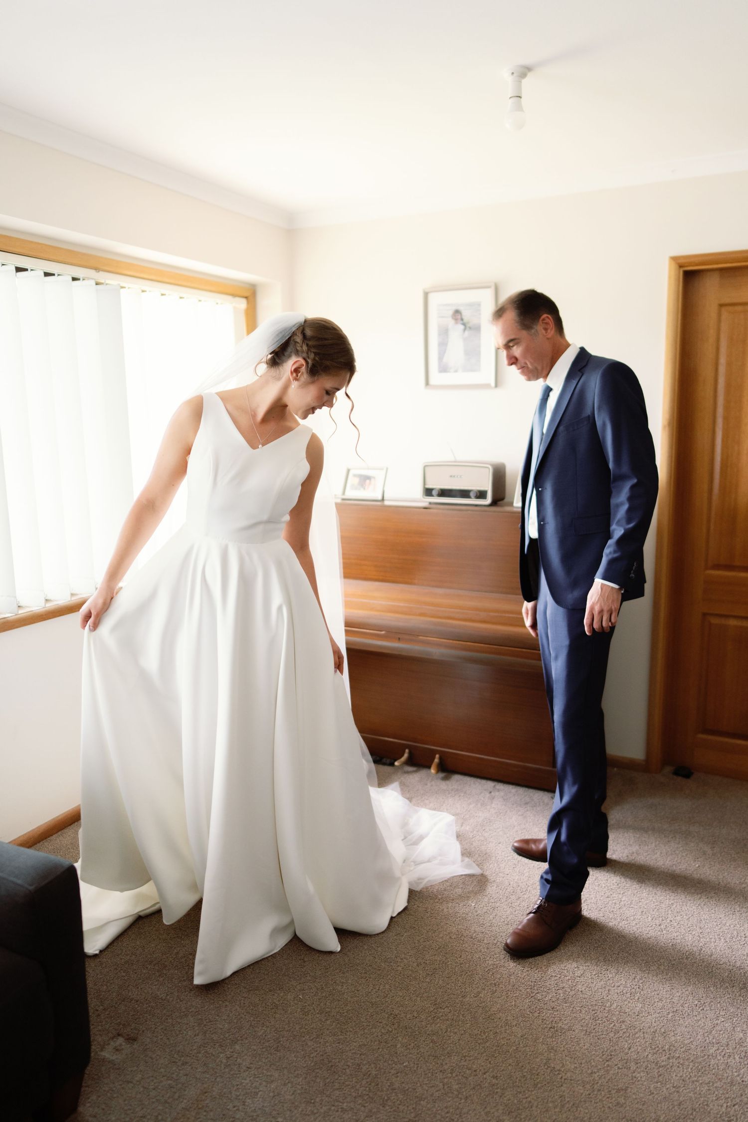 A bride in a flowing white wedding gown twirls in a room while others watch.