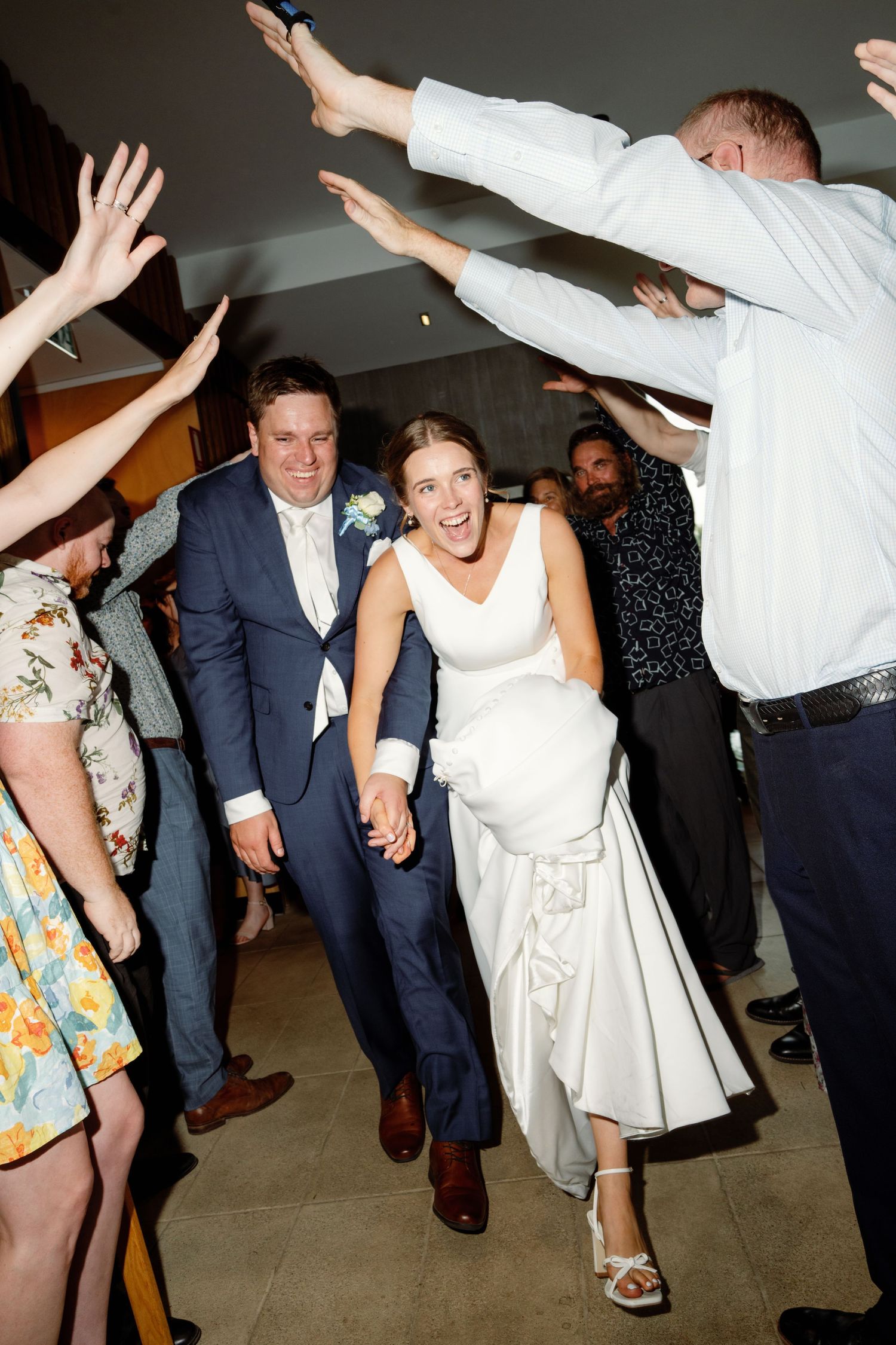 Wedding reception dance party with guests raising hands and celebrating on the dance floor.