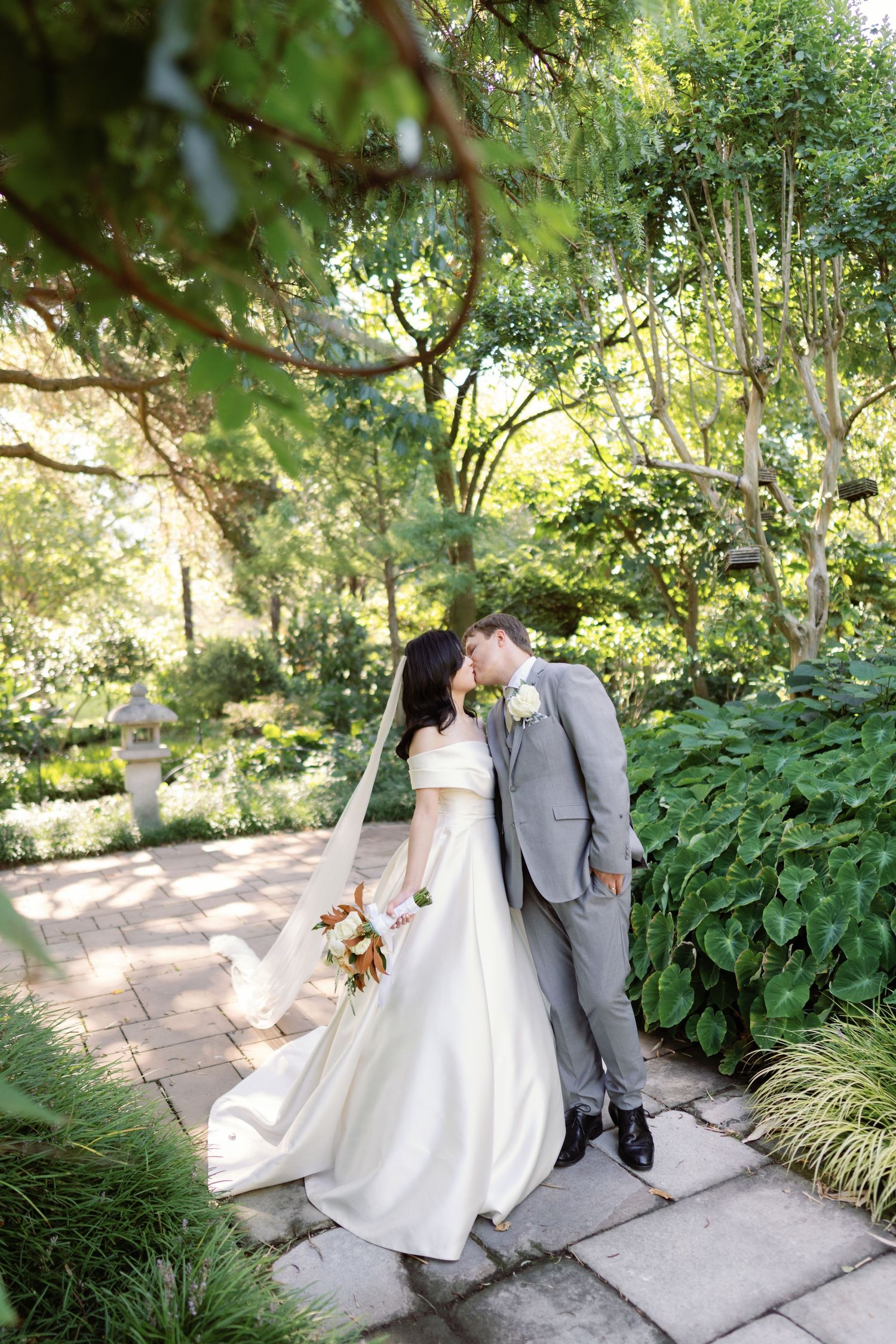 Romantic wedding photos of couple walking along garden pathway.