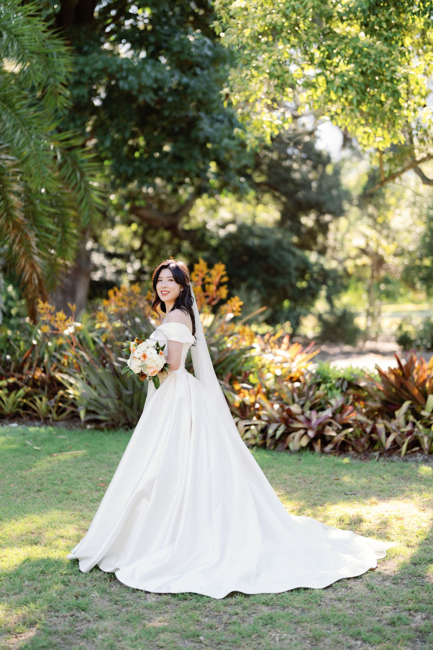 A stunning bridal portrait series in a lush garden setting showcasing an elegant white ballgown wedding dress.