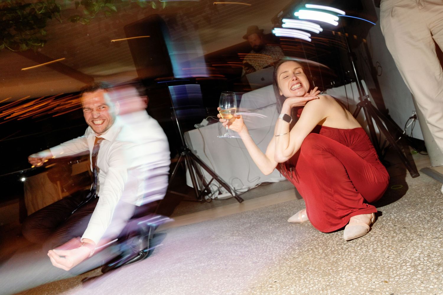 Wedding guests dancing energetically at lively reception celebration with champagne glasses.