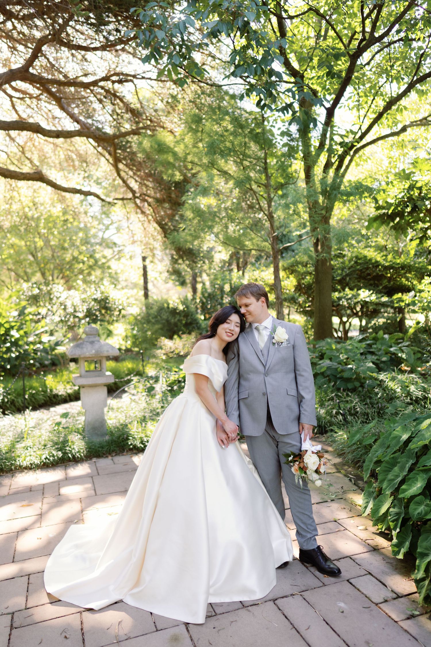 Romantic wedding photos on stone pathway surrounded by garden landscaping.