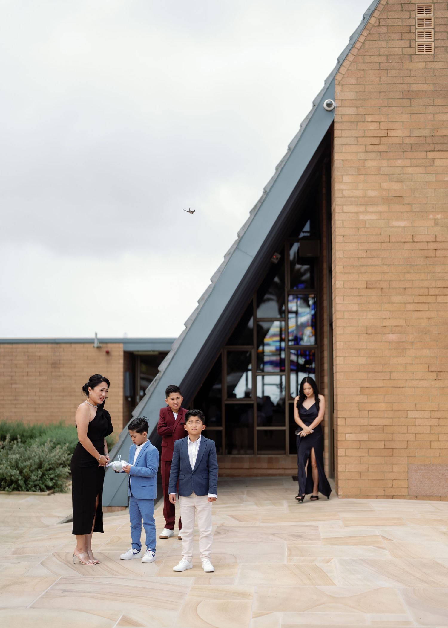 Modern brick building exterior with angular architecture and paved courtyard.