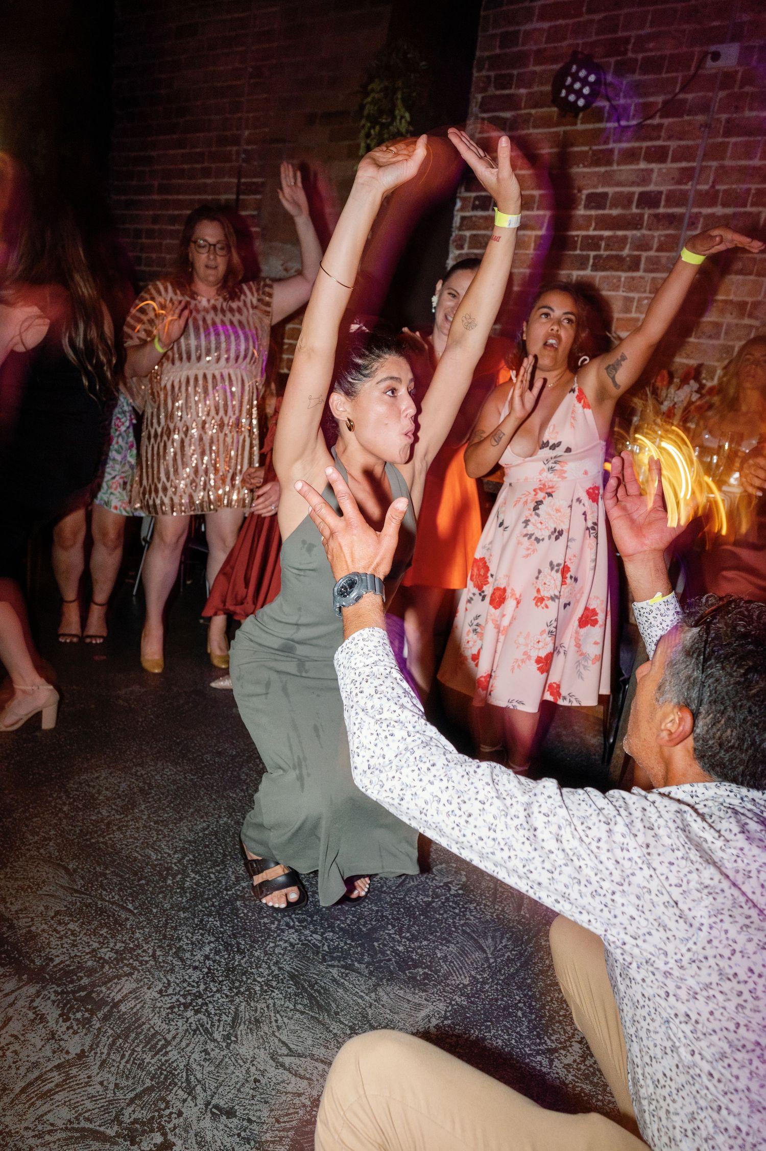 People dancing and having fun at a party with brick walls in the background.
