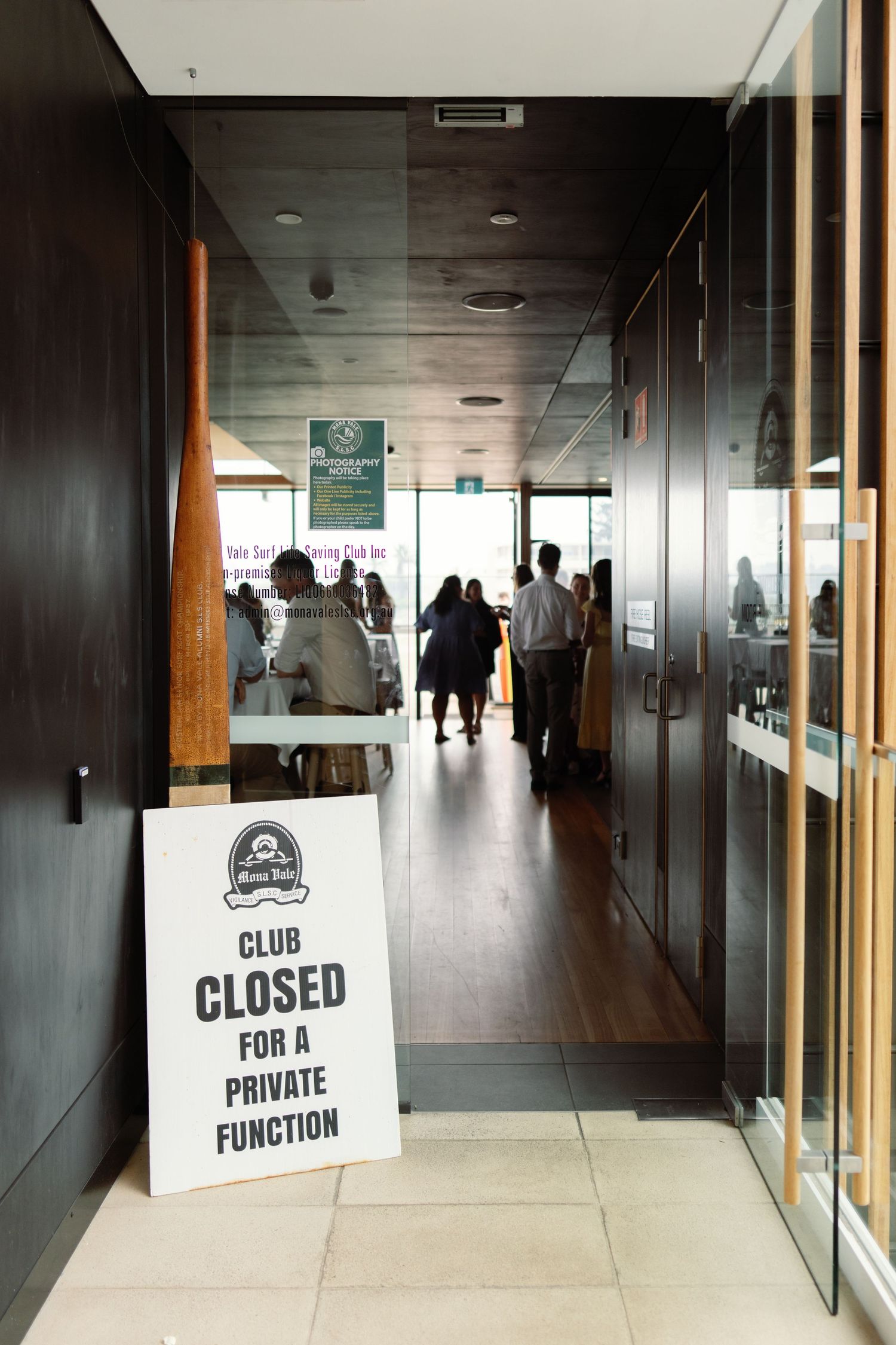 Empty hallway with dark wood panels and glass walls displaying 'Club Closed for Private Function' signs.