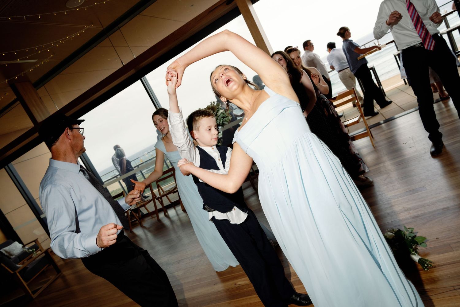 Wedding reception dance floor with guests dancing under dim lighting at an indoor venue.
