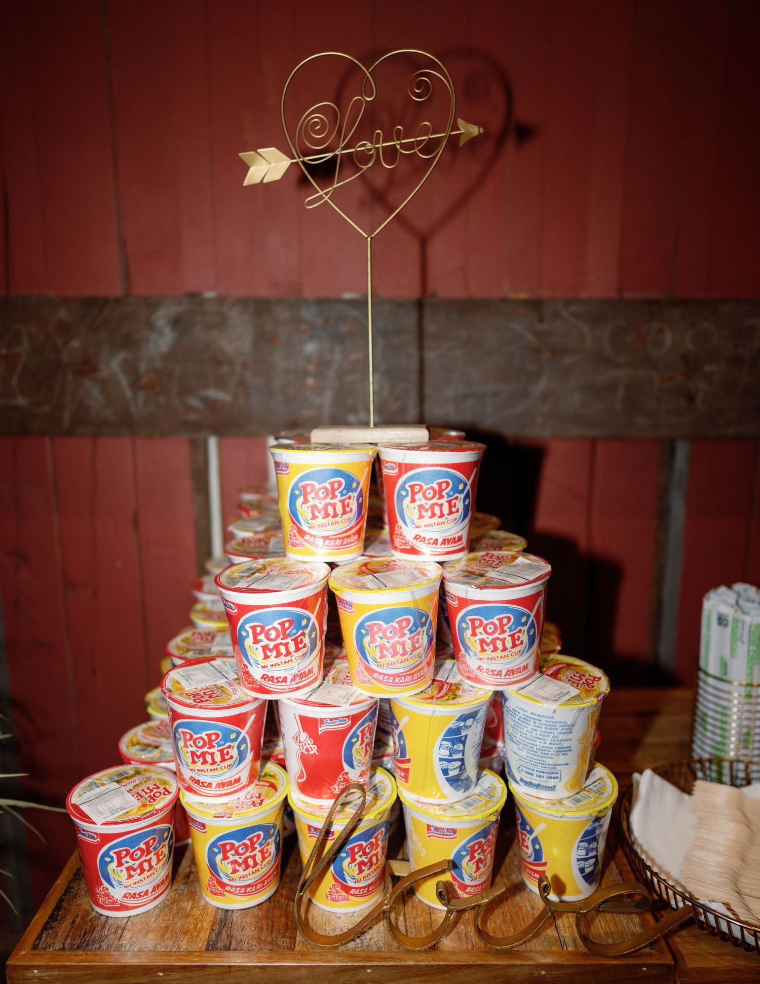 Ice cream cups arranged in ascending order on a rustic wooden surface against a dark red background.