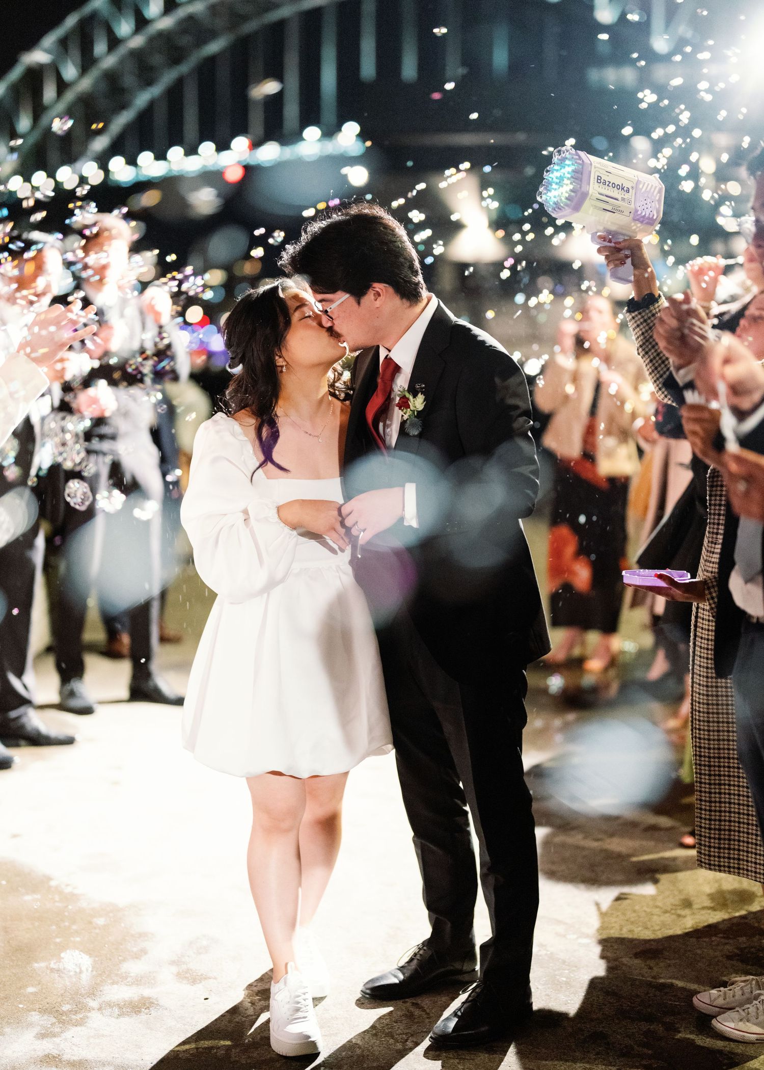 A couple shares a romantic dance under sparklers at their wedding reception as guests hold up lights around them.