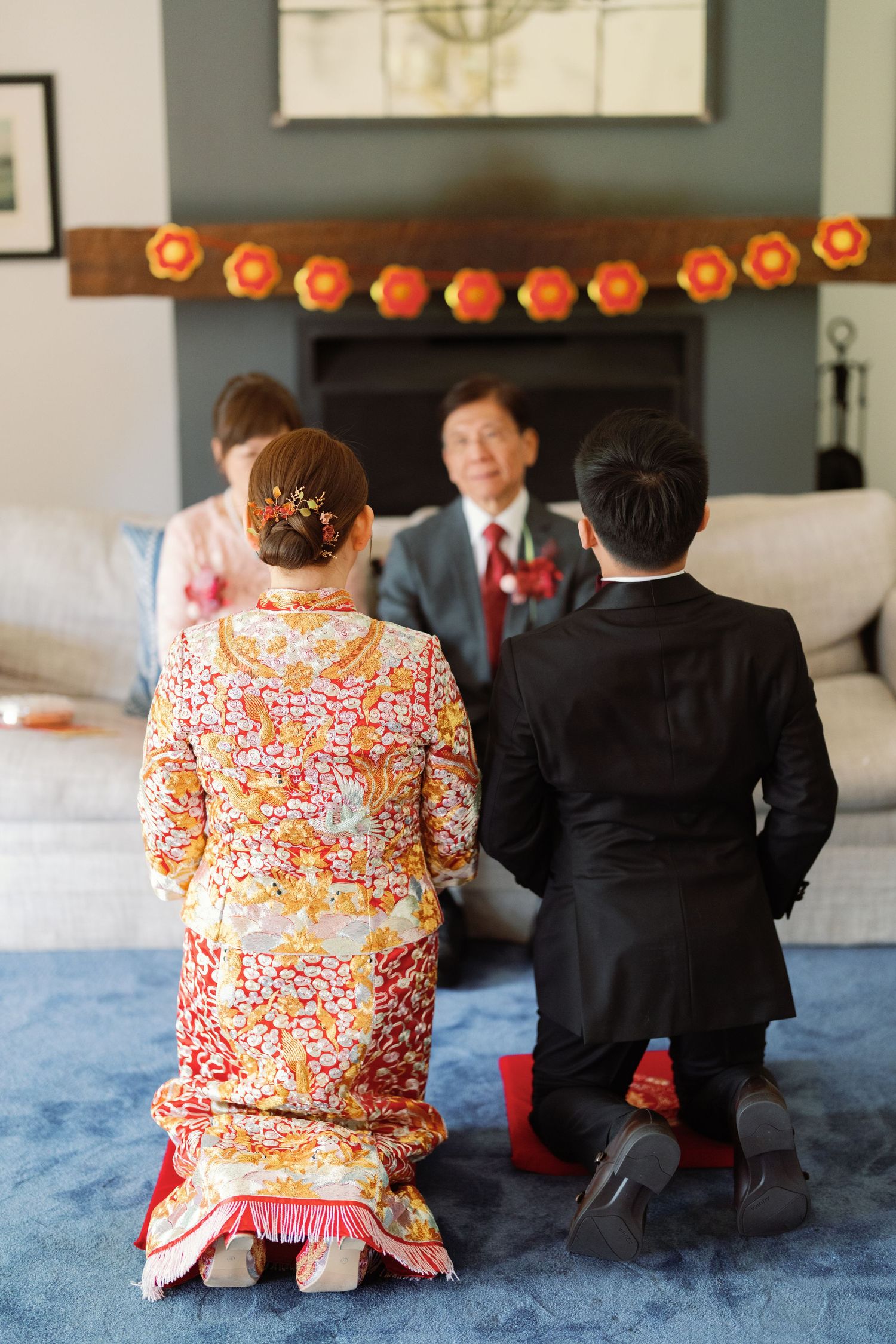 Traditional tea ceremony with participants kneeling on blue carpet under orange lantern decorations.