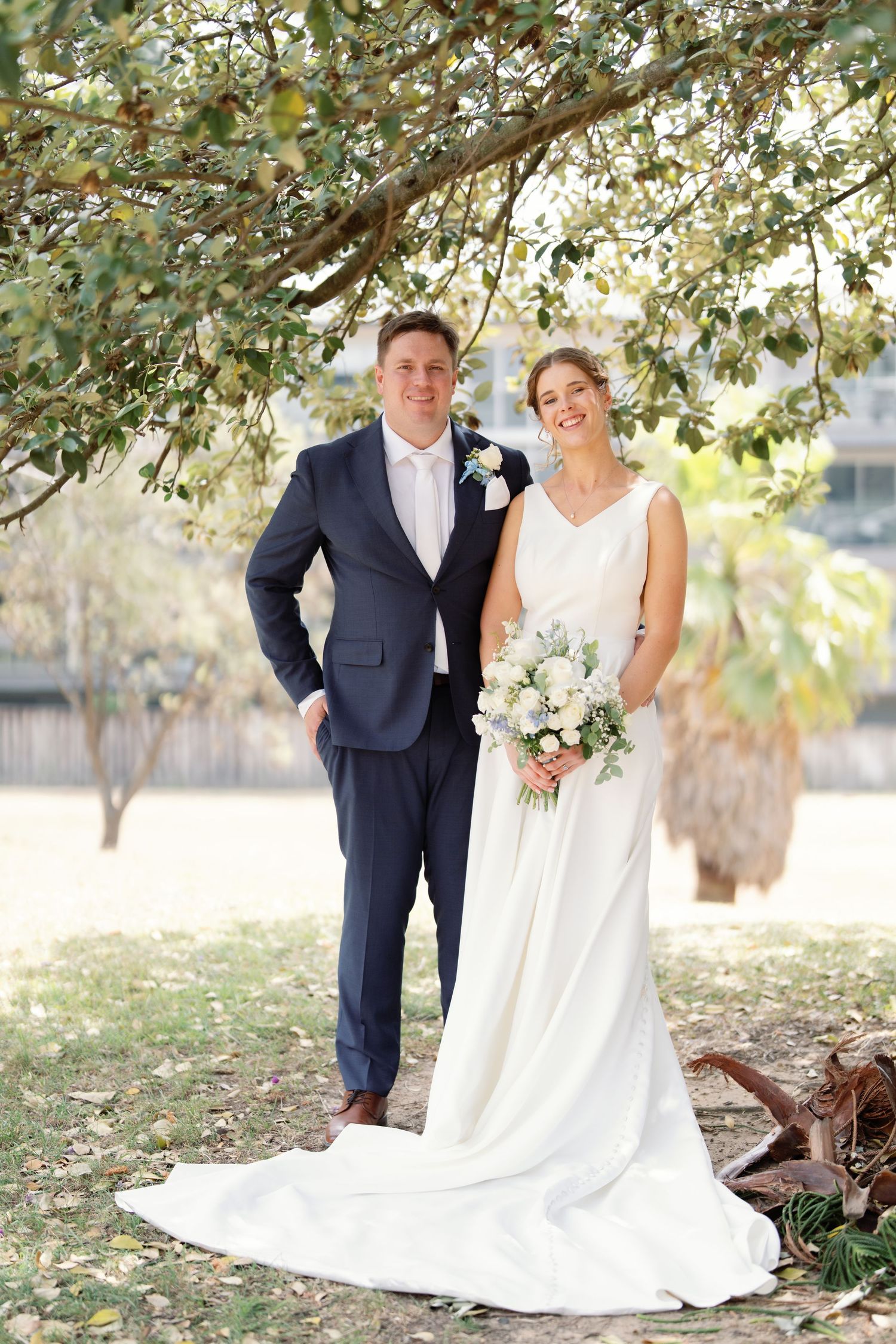 Elegant wedding portraits captured under dappled sunlight and tree branches.