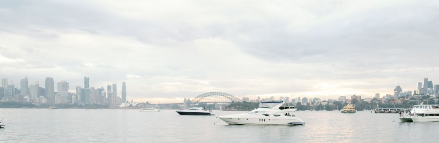 A tranquil harbor view with boats and city skyline in the misty distance.