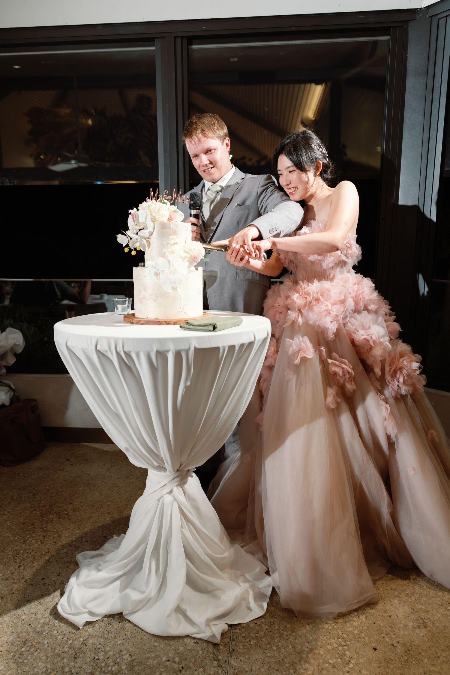 Wedding cake cutting sequence at reception with couple in white and pink attire.
