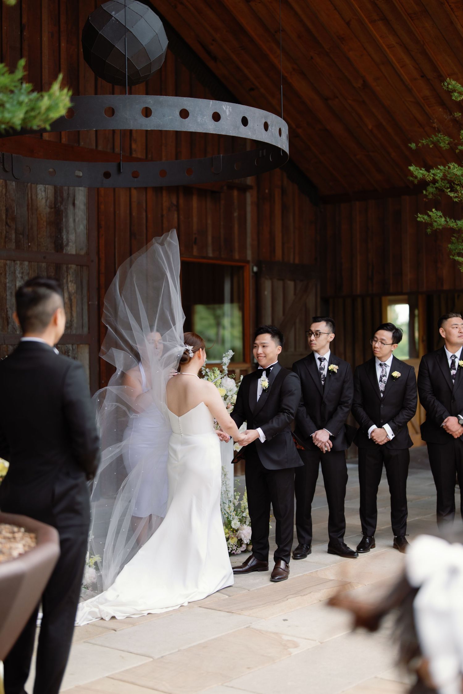 Wedding ceremony taking place in a rustic wooden barn with elegant white decor.
