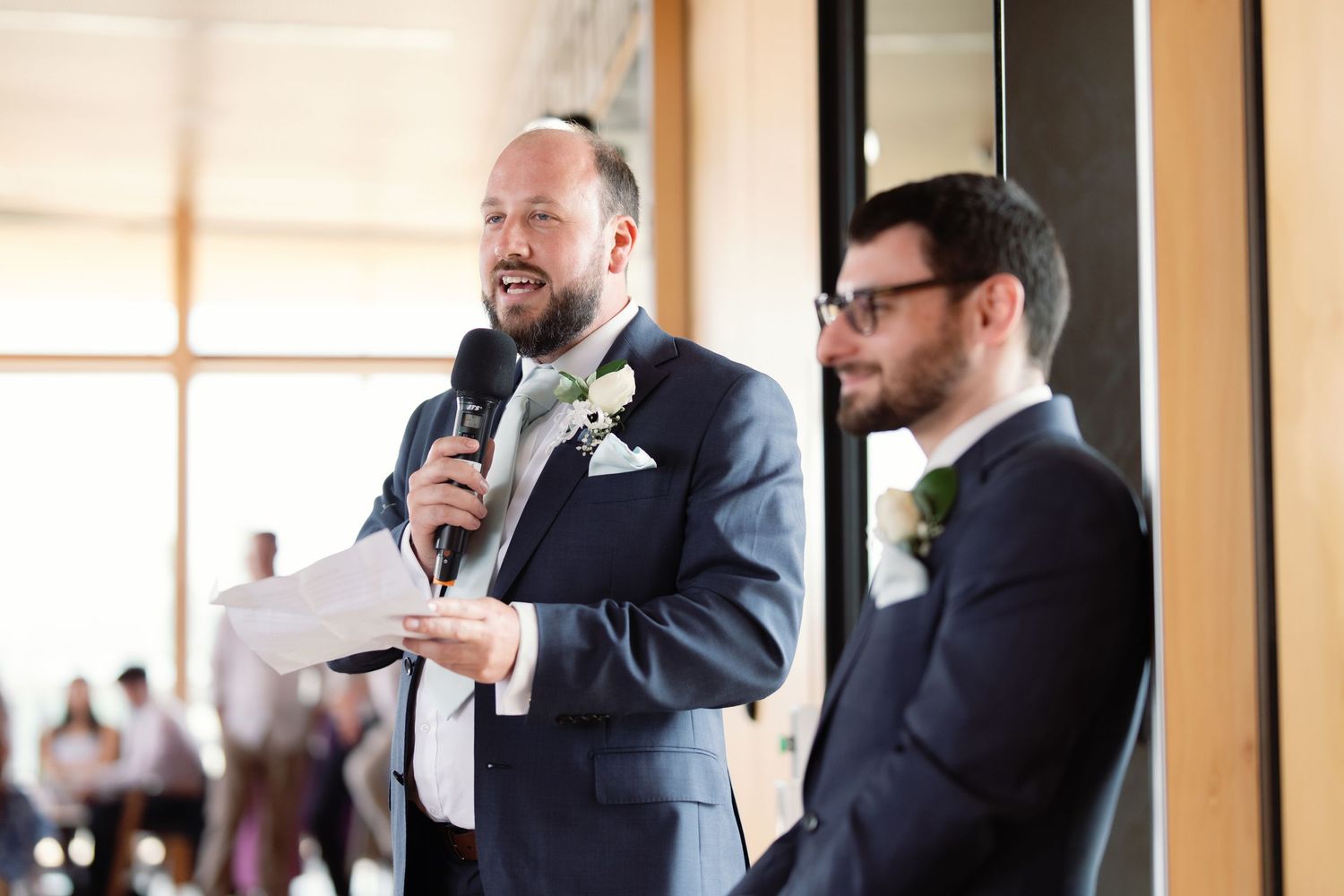 Wedding party members in formal attire sharing laughs during indoor celebration.