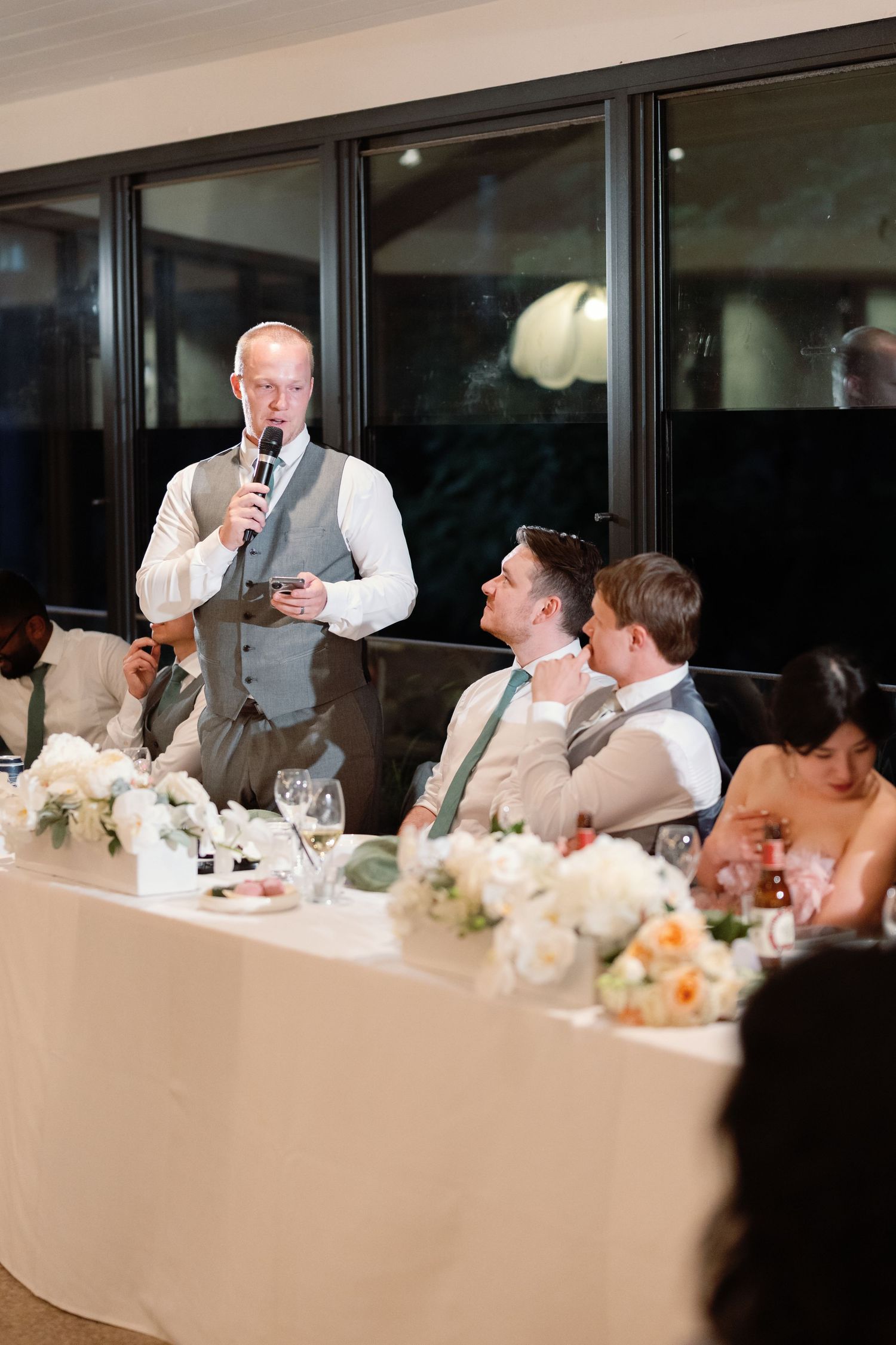 Wedding reception dinner with guests seated at decorated tables during speeches.