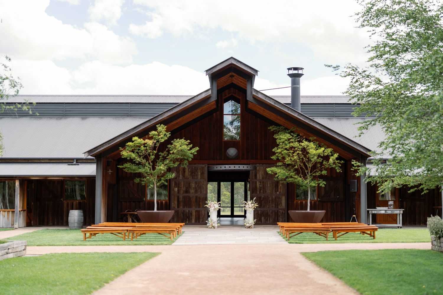 Modern wooden lodge-style building exterior with long walkway and trees.