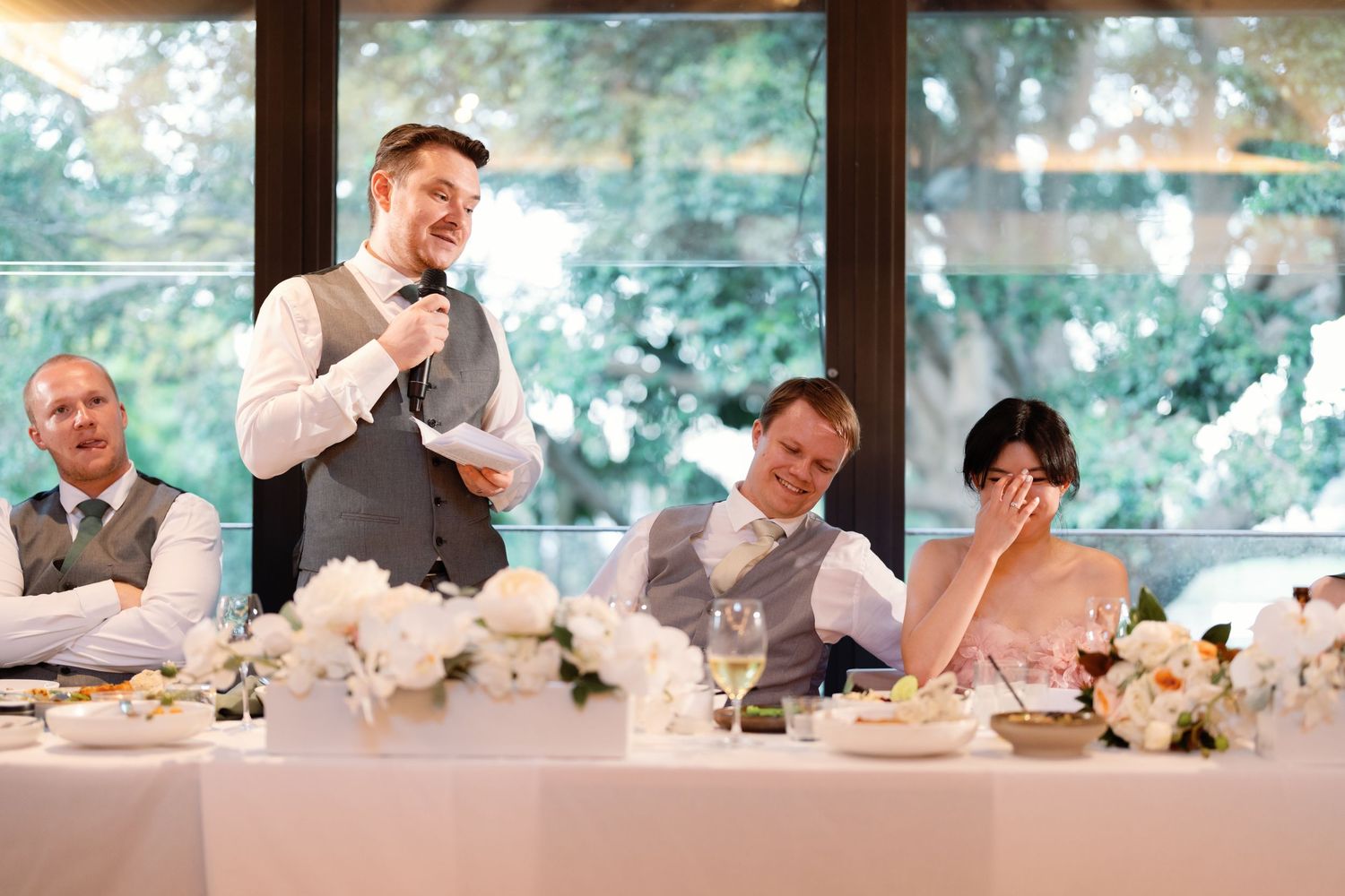 Wedding reception candid moments captured at head table with natural window lighting.