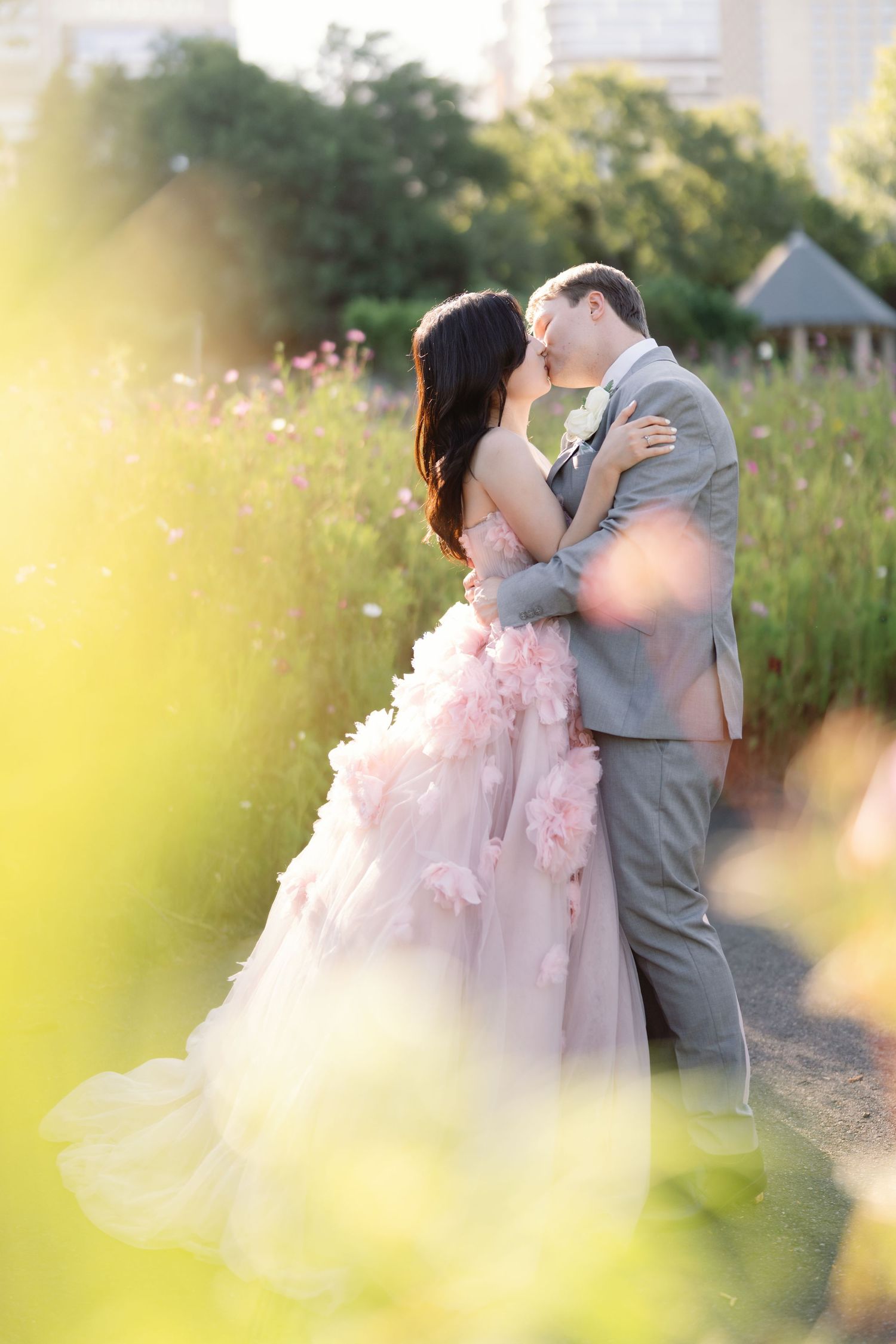 Dreamy wedding portraits of a couple embracing in a sunlit garden with pink floral details.