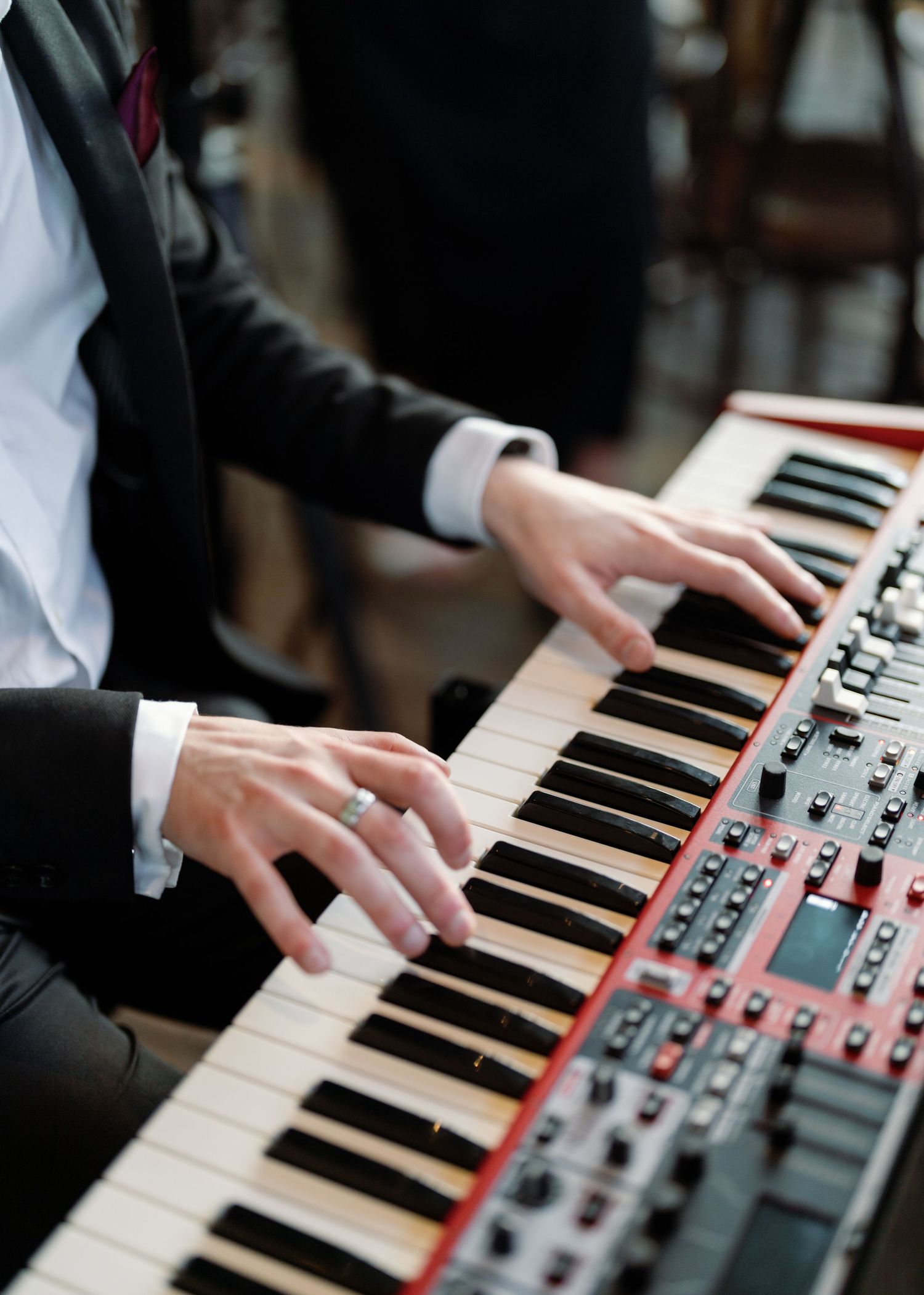 Close-up shots of hands playing a red Nord synthesizer keyboard at an event.