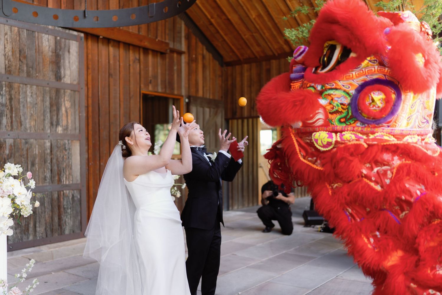 A couple reacts excitedly to a traditional red Chinese lion dance performer at their wedding.