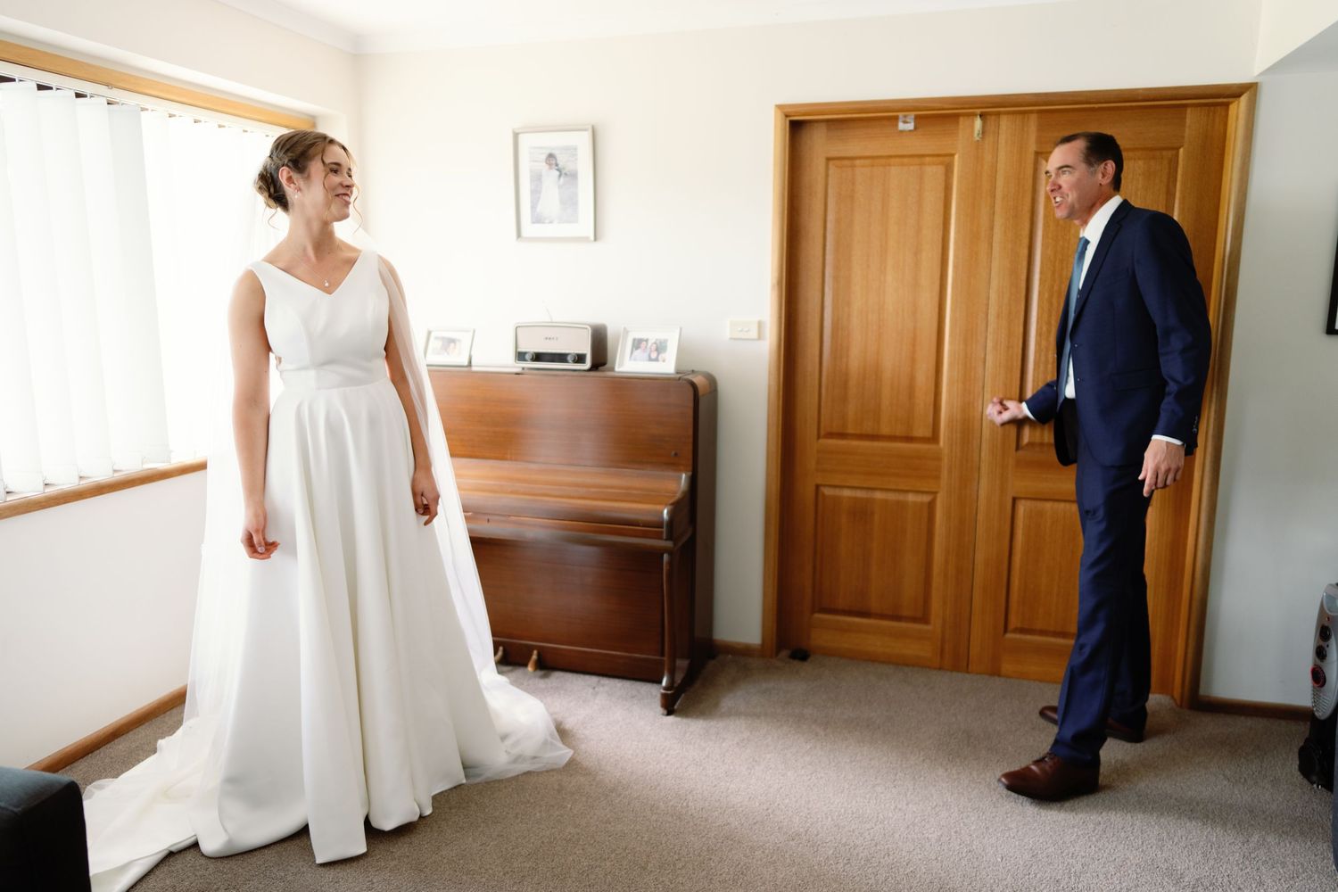 Wedding preparation scene showing a white bridal gown and wooden door in a bright interior hallway.