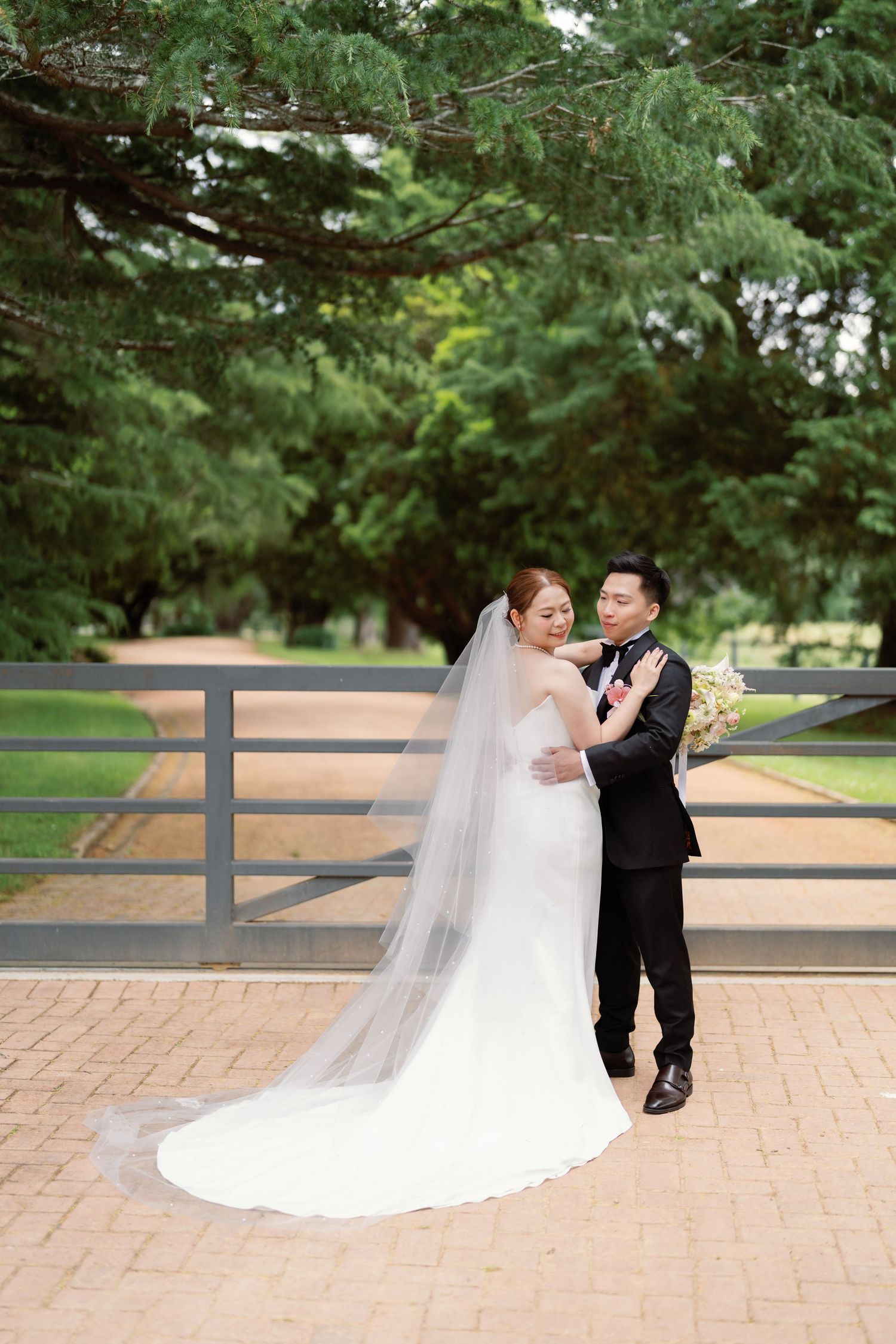 A couple shares a romantic moment on brick pavement with a flowing white wedding dress.