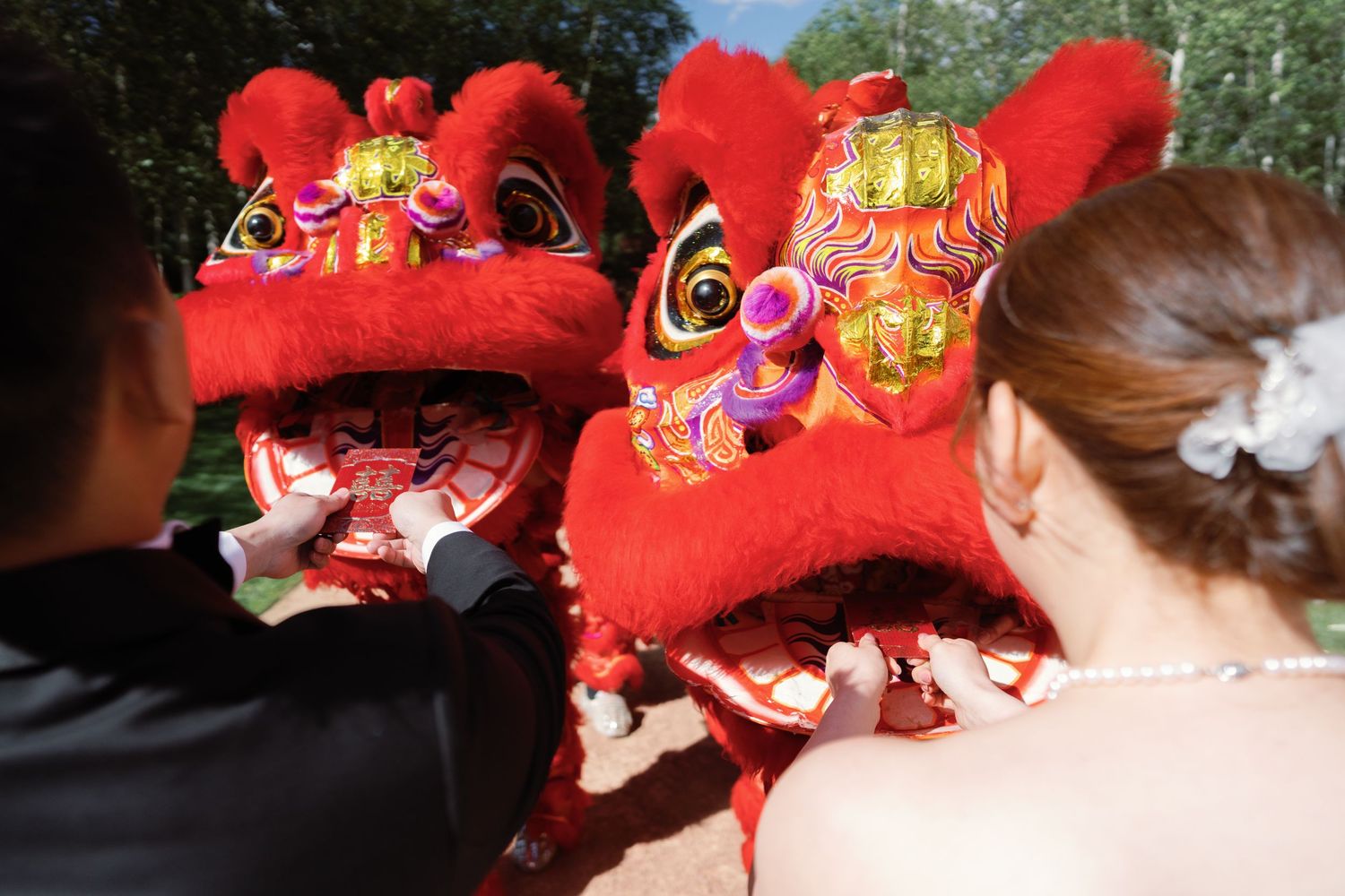 Traditional red Chinese lion dance headpieces lined up during wedding celebration.