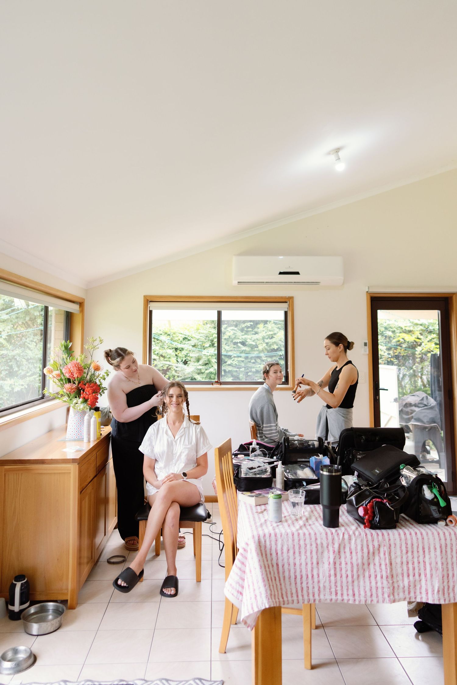 Wedding preparation scene in a bright room with makeup artists and stylists getting ready for the big day.