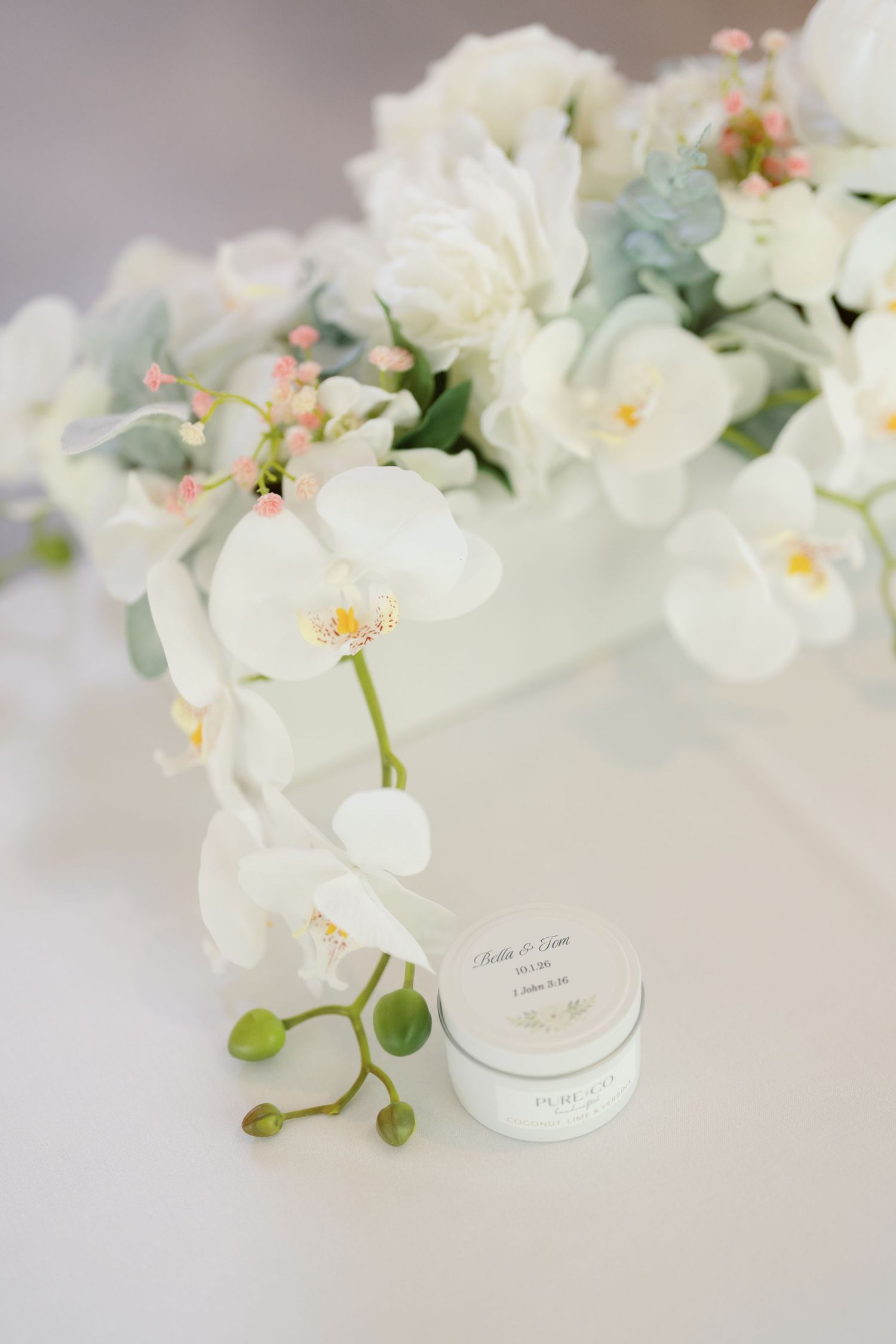 White orchids arranged in elegant vases against a soft gray background.