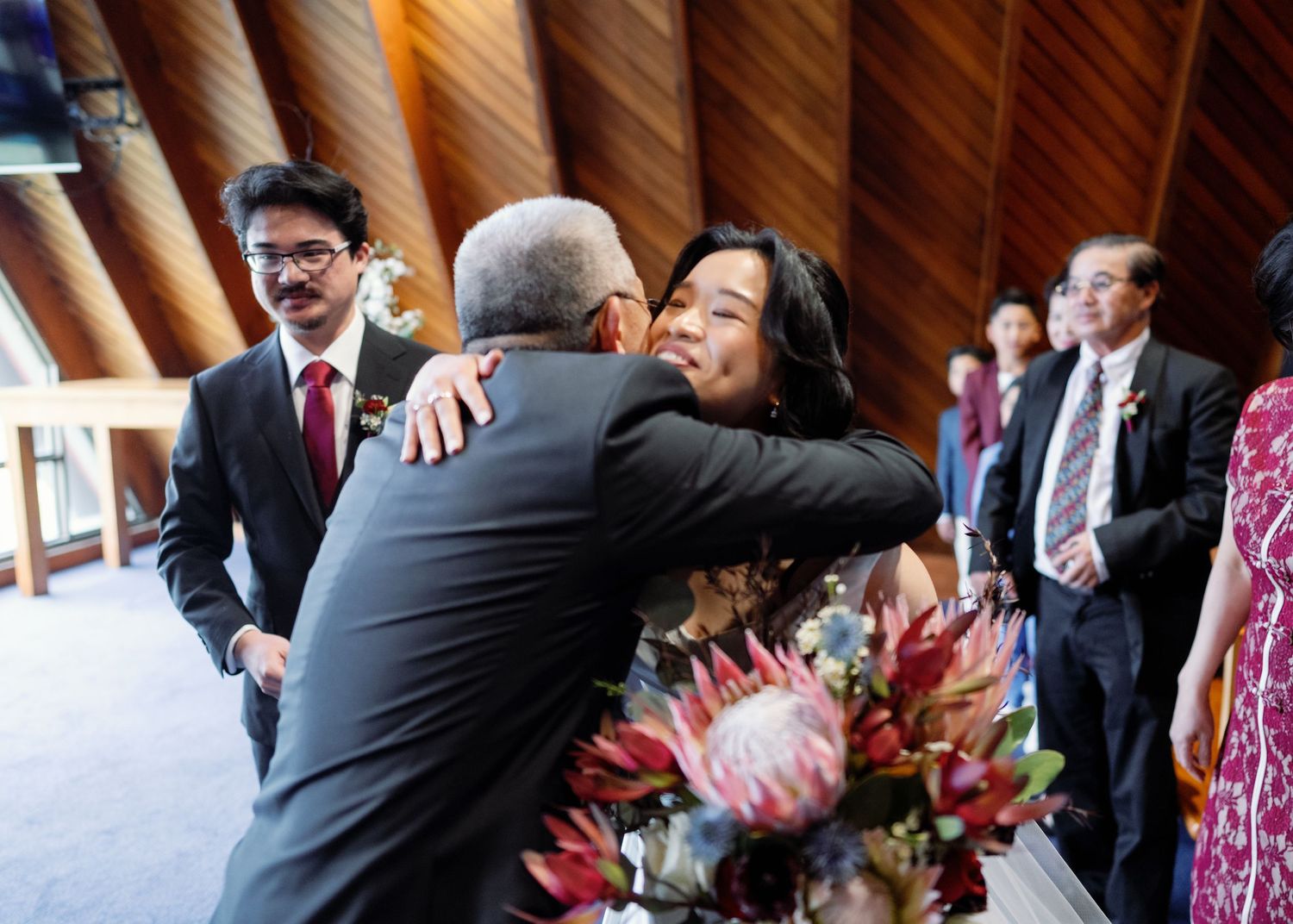 Wedding guests celebrate and dance during a festive reception with vibrant pink floral arrangements.