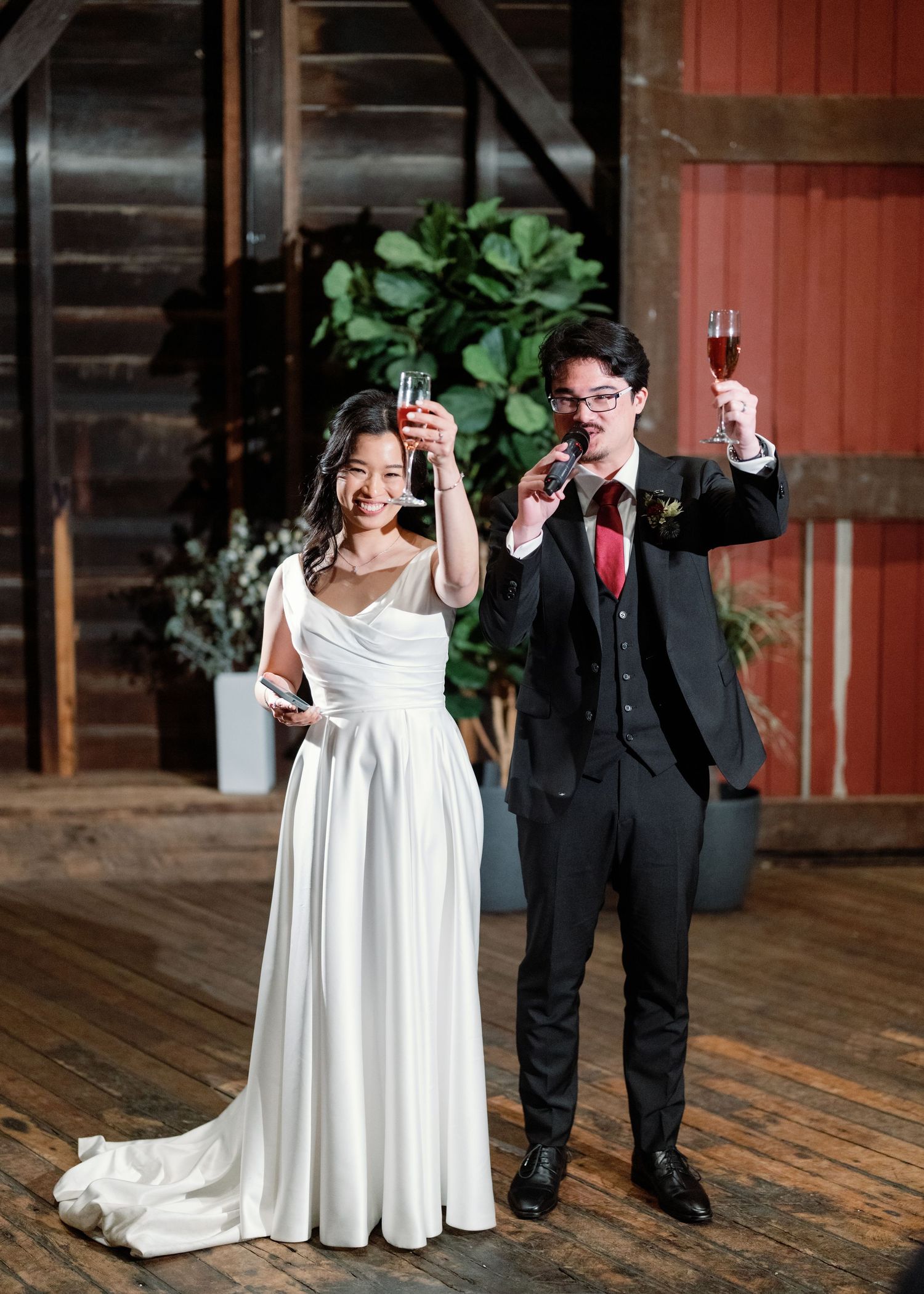A joyful wedding couple dances and celebrates in a rustic barn venue with wooden floors.