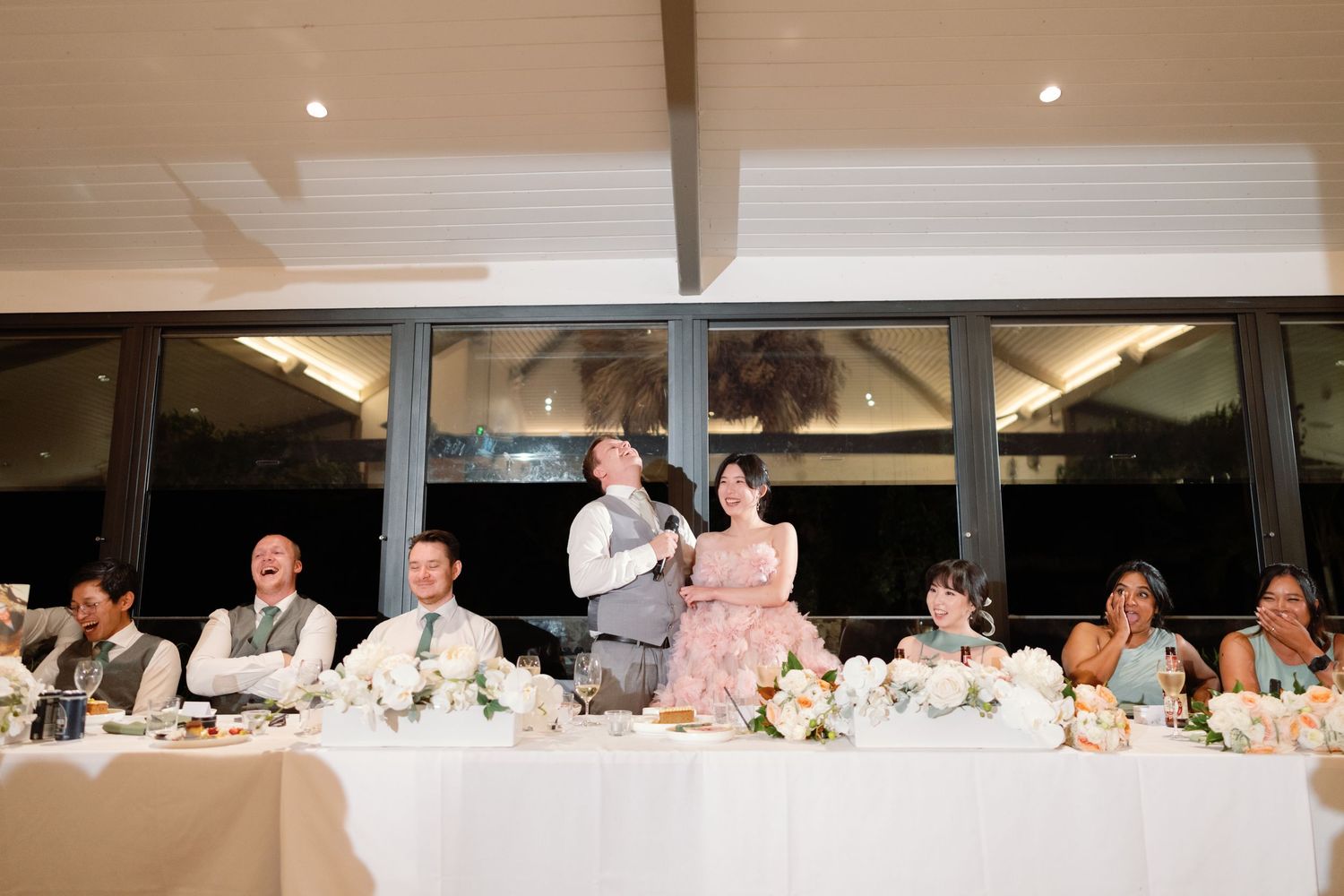 Panoramic view of an elegant wedding reception with guests seated at long tables.
