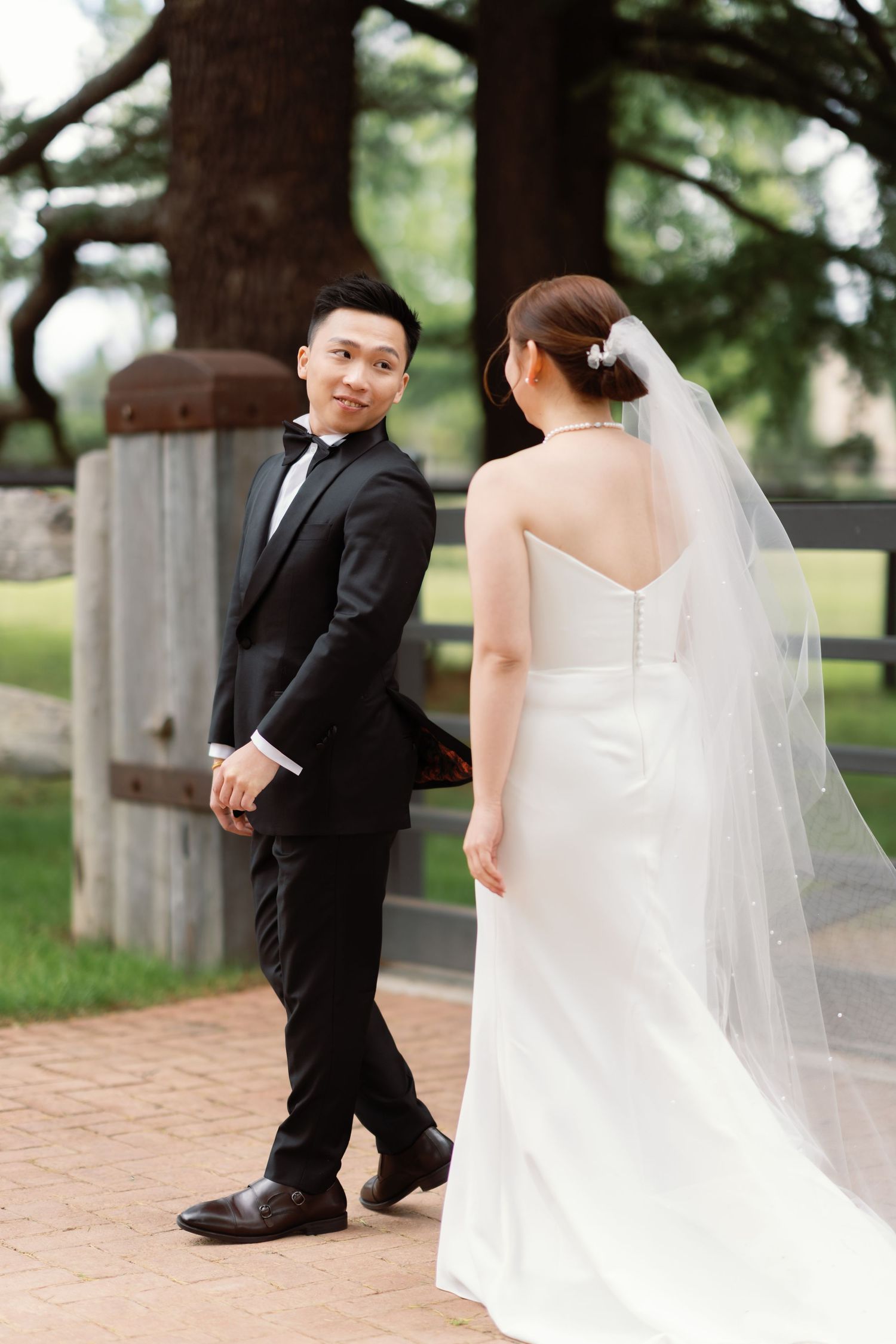 Wedding couple takes romantic photos on brick pathway in outdoor garden setting.