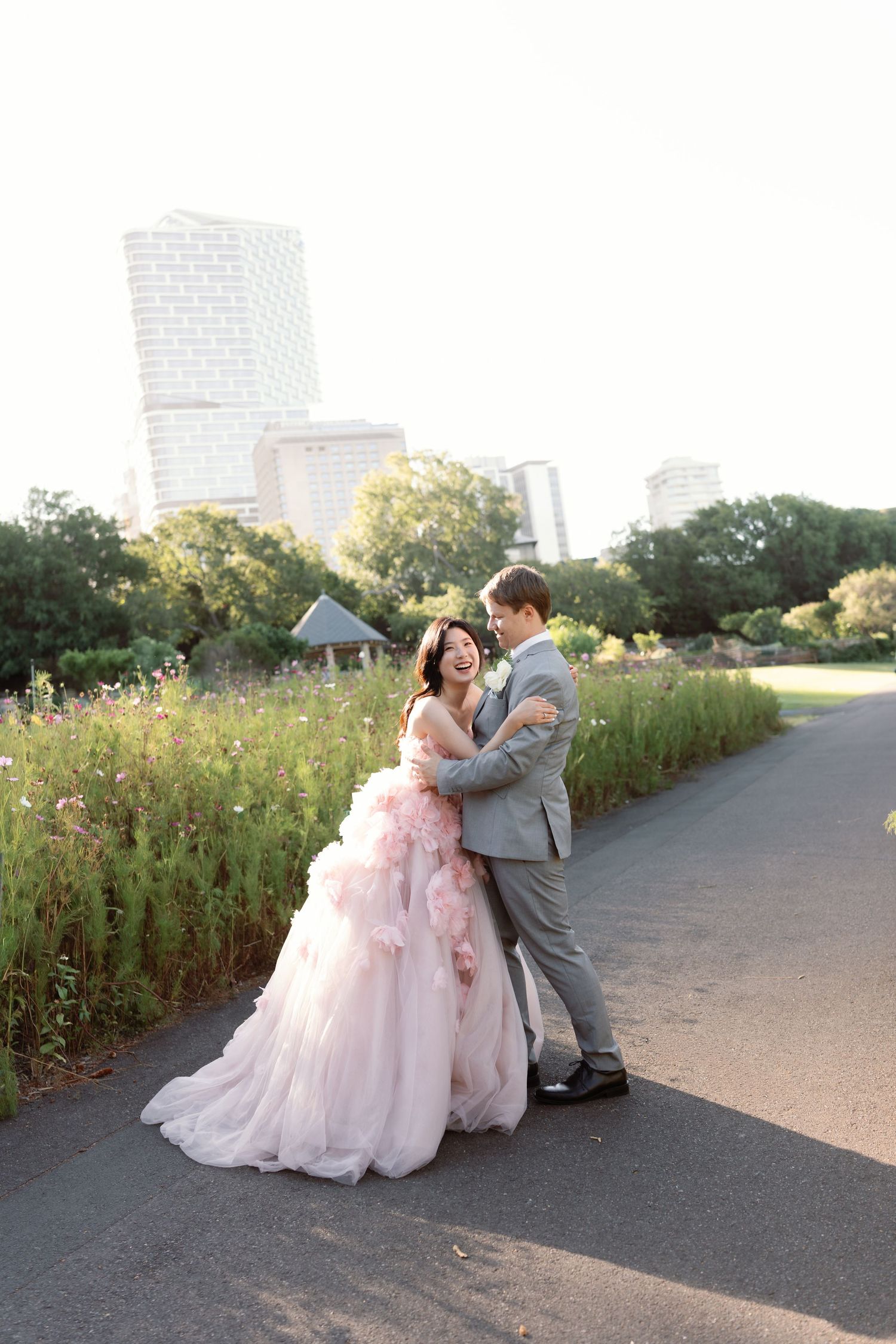 Romantic wedding photos of a couple in a garden setting with city skyline in background.