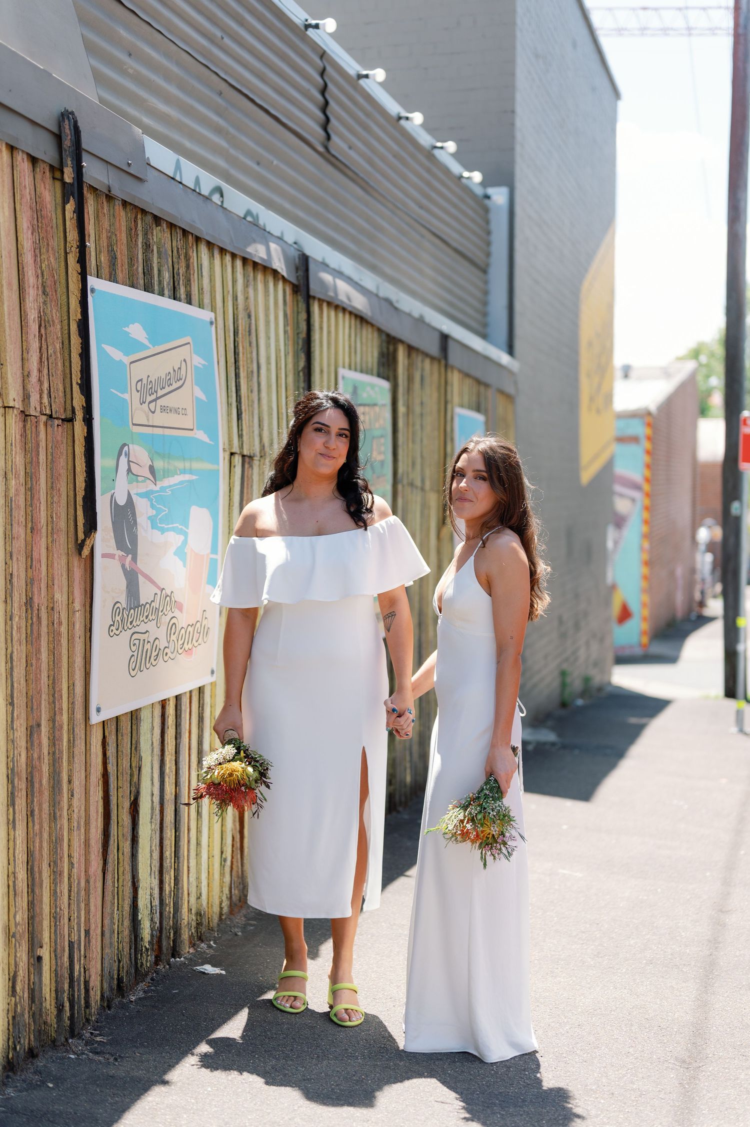 A series of artistic wedding photos showing a couple in white dresses walking along an urban wall with posters.