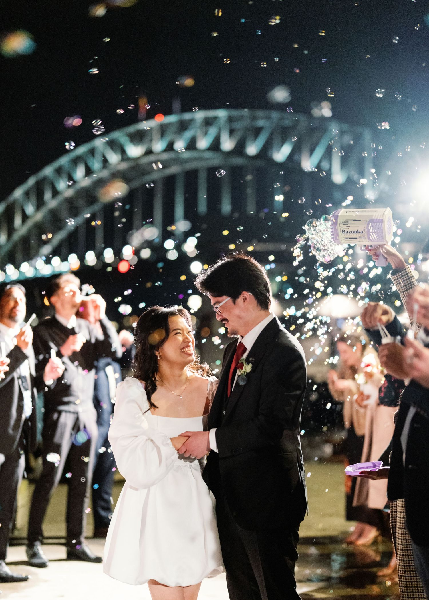Nighttime wedding celebration with sparklers and Sydney Harbour Bridge in background.