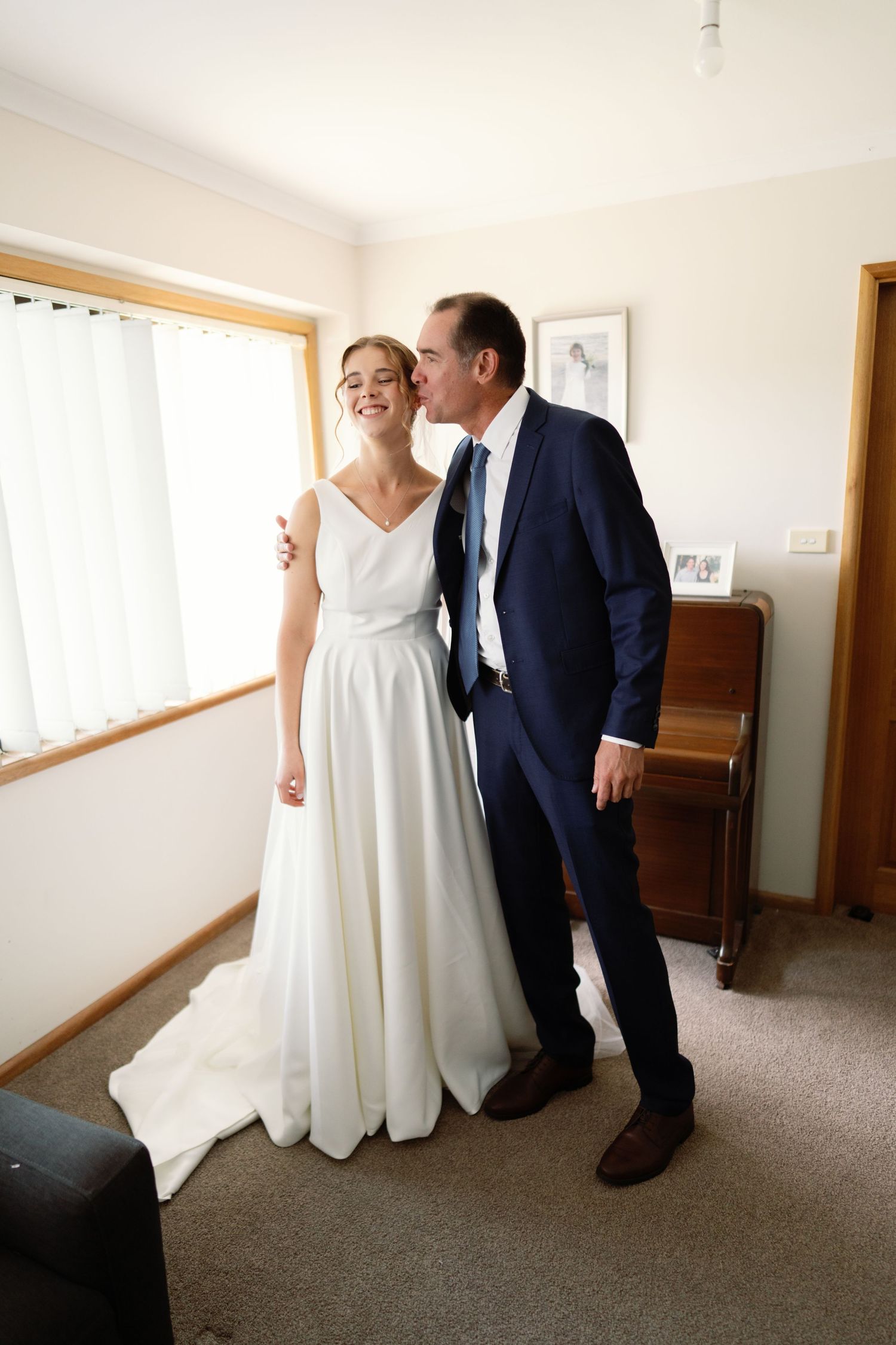 A couple shares a tender first look moment in a hallway before their wedding ceremony.