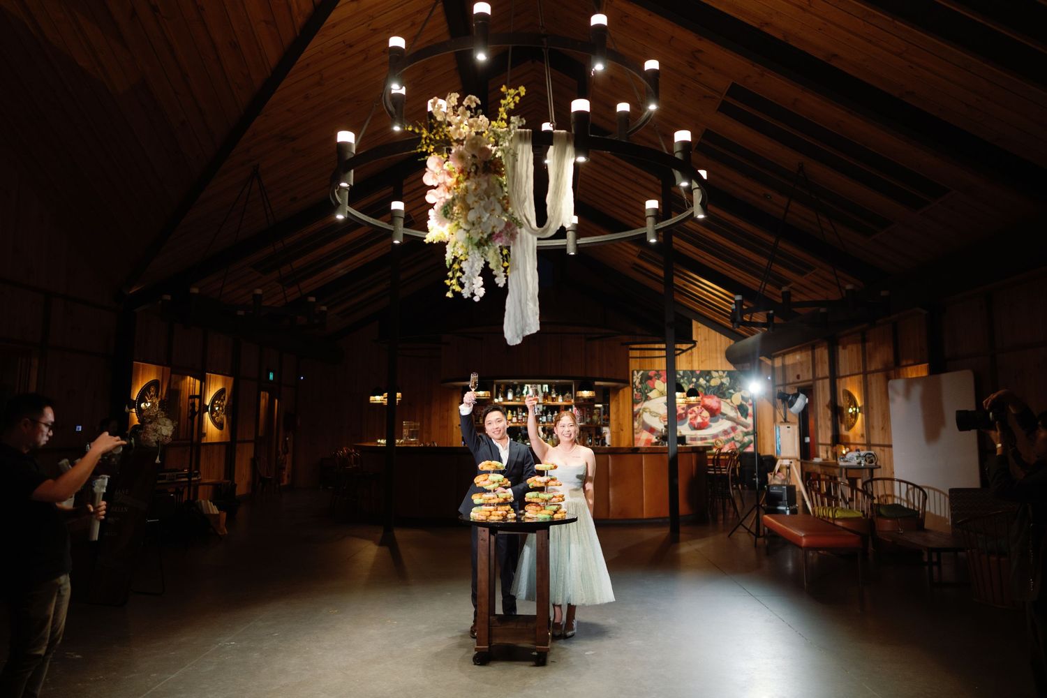 Interior of rustic barn wedding venue with hanging lights and wooden beams.