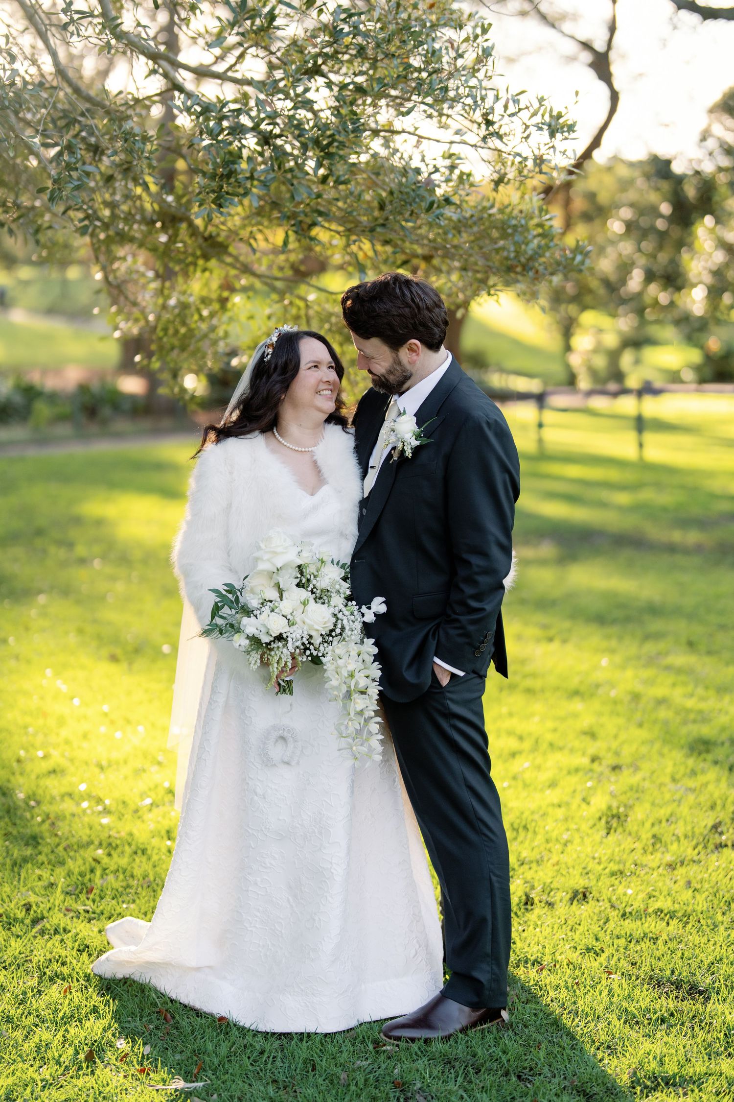 Bride and groom sharing an intimate moment laughing together outdoors in golden hour light on their wedding day.