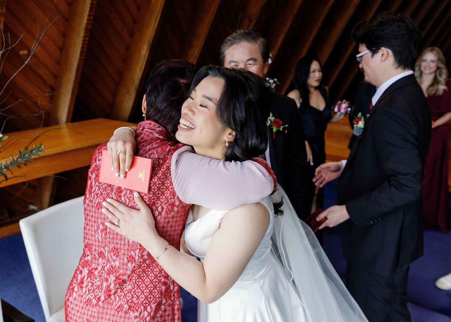 Wedding celebration with guests in formal attire inside a wooden chapel.