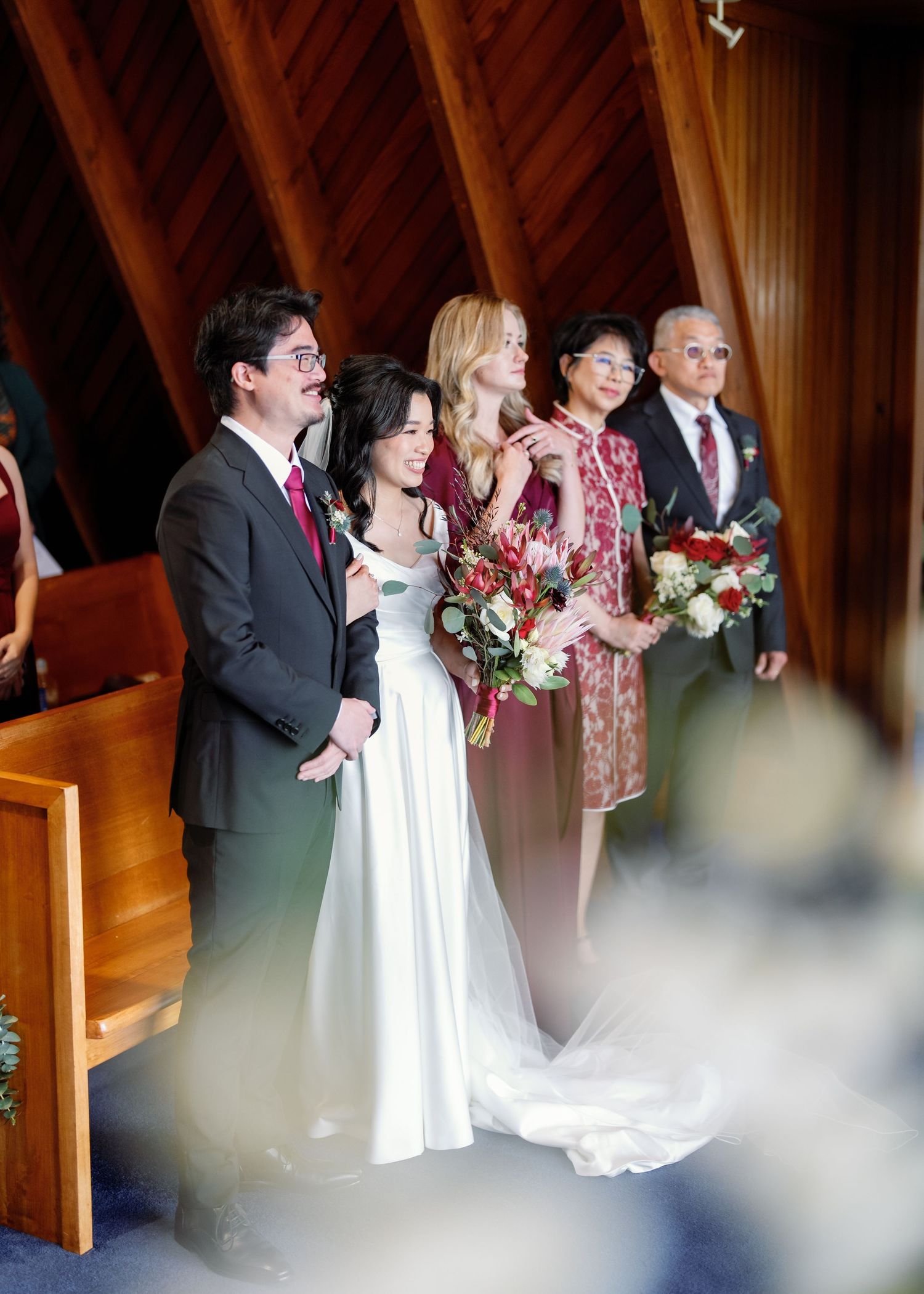 Wedding ceremony in a rustic wooden chapel with stained glass windows and exposed beams.