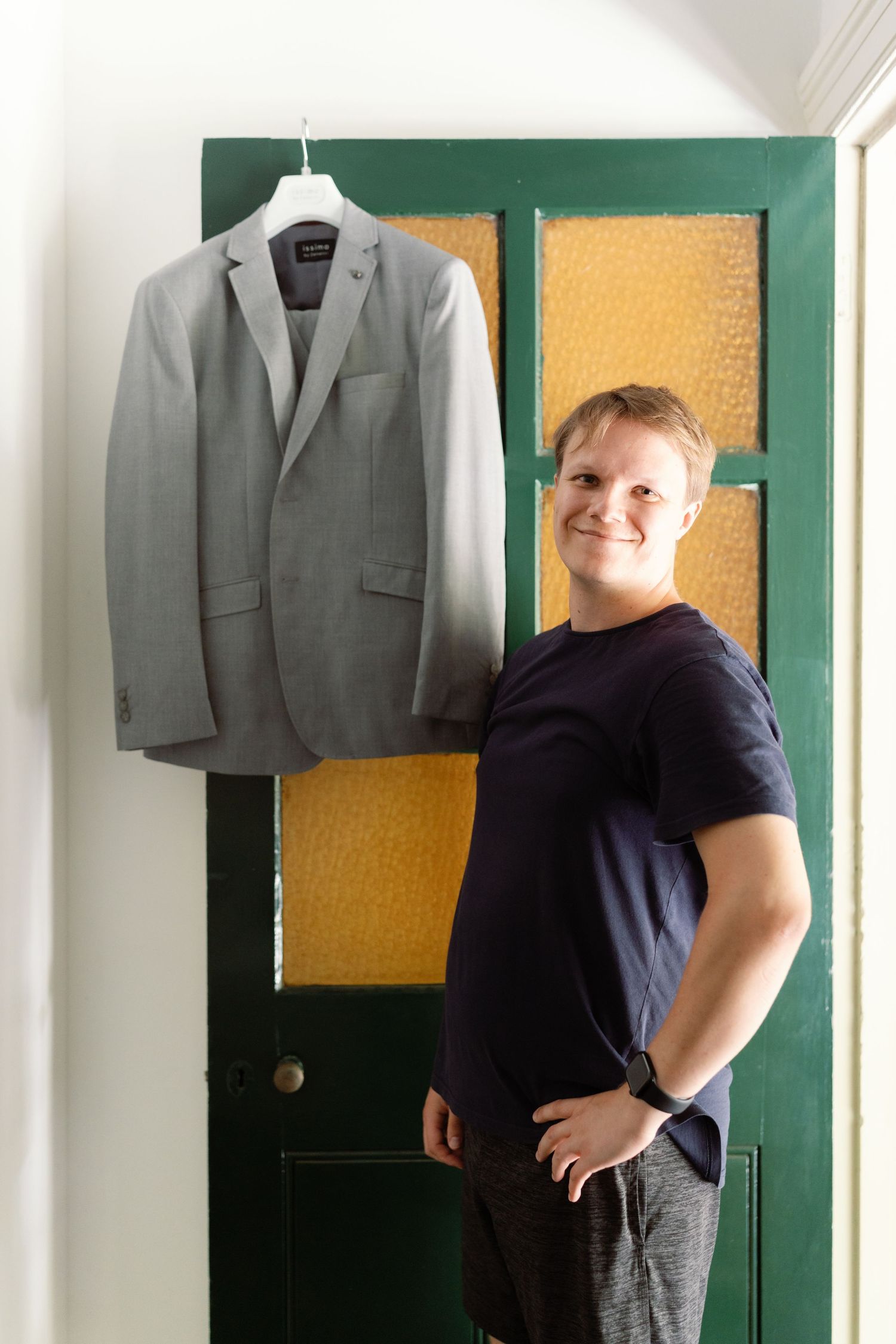 A gray suit jacket hangs on display against a green and yellow wall.