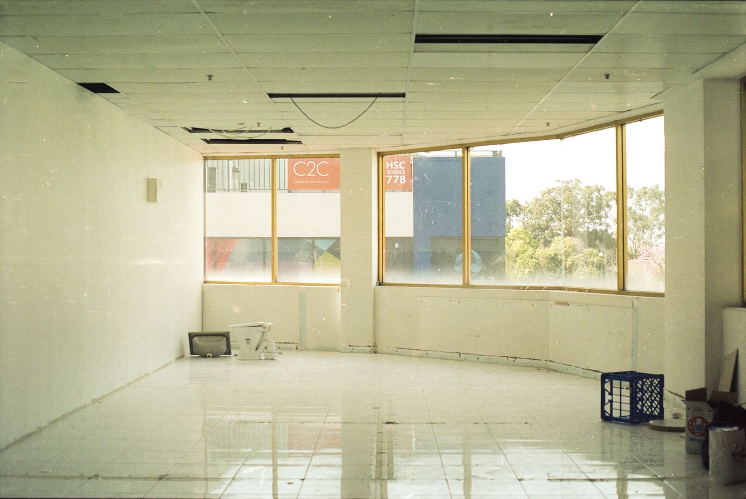 Empty commercial space with white walls, tiled floors and large windows letting in natural light.