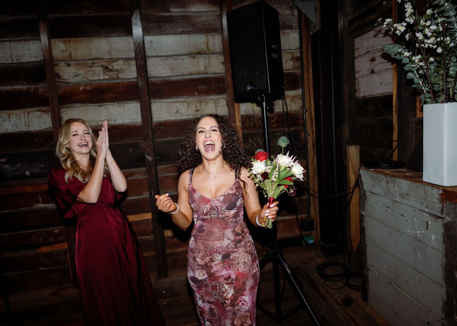 Wedding celebration inside a rustic wooden barn venue with festive lighting and decor.