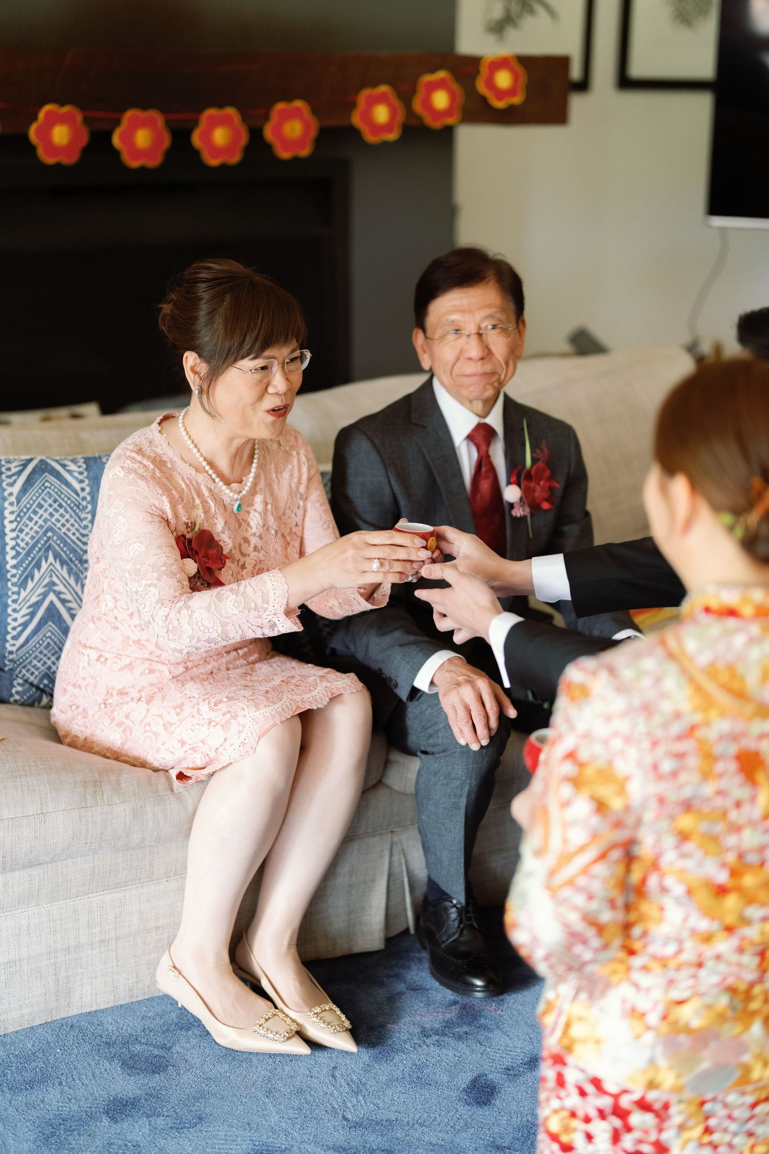 Two people sit on a blue couch having an animated conversation in formal attire.
