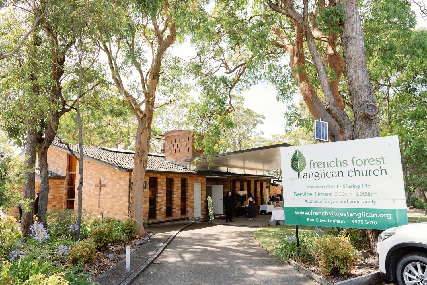 Exterior view of a church building surrounded by mature trees and greenery.