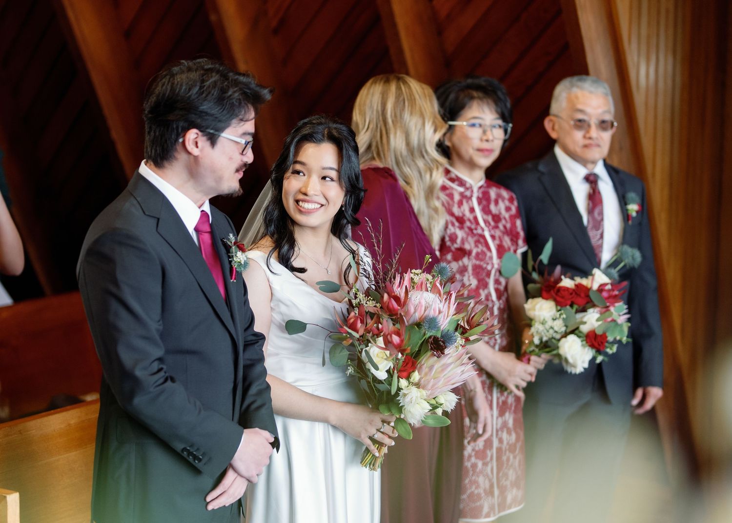 Wedding party members laugh and celebrate together in a candid moment at an indoor venue.