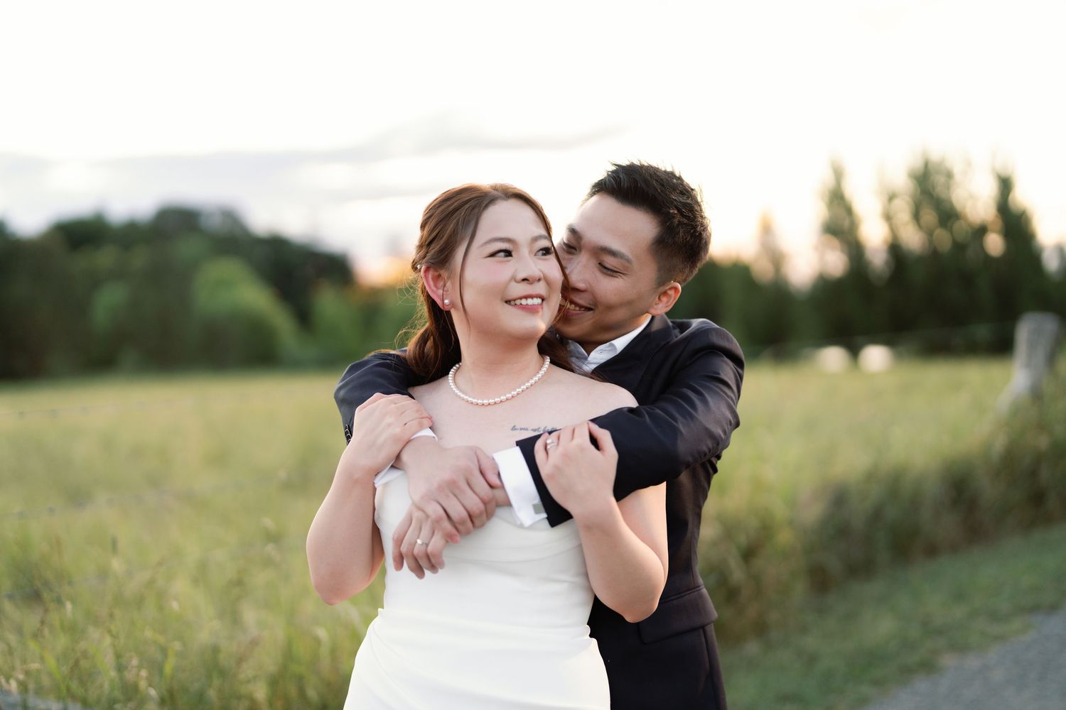 Romantic outdoor wedding portraits captured in a sunlit field at golden hour.