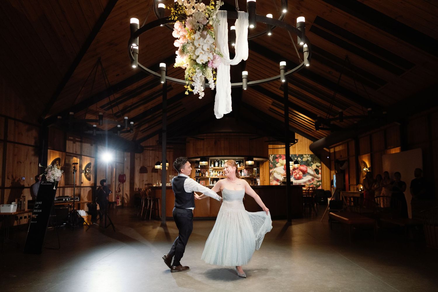Wedding reception dance floor scene with dramatic lighting in barn venue.