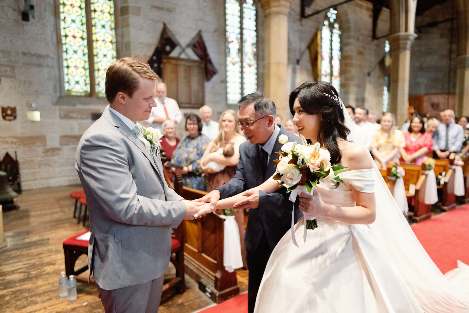 Wedding ceremony taking place inside a historic church with stained glass windows.